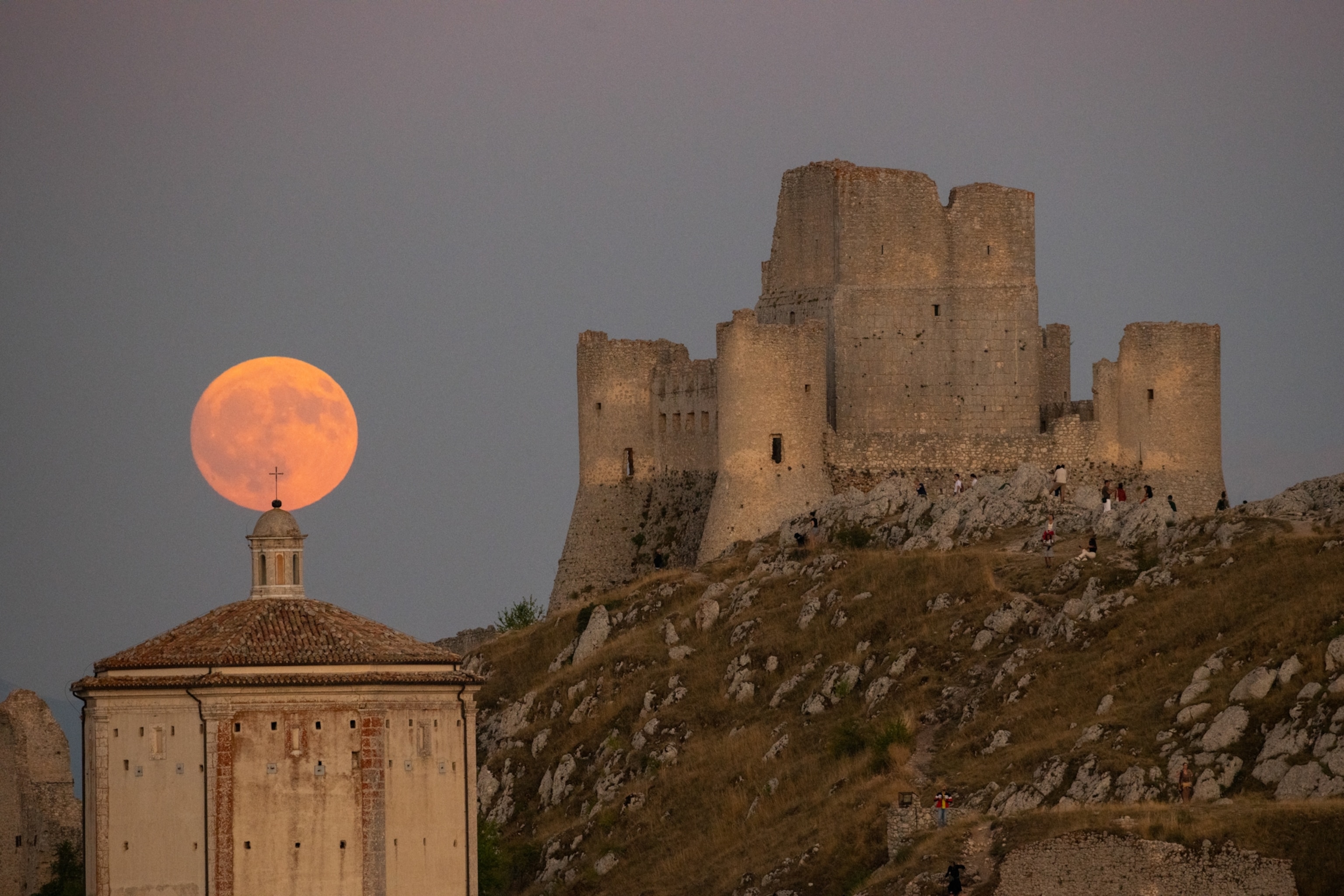 Sturgeon full moon rising behind Rocca Calascio castle and Santa Maria della Pietà Church is seen in Rocca Calascio, Italy, on August 8th, 2025