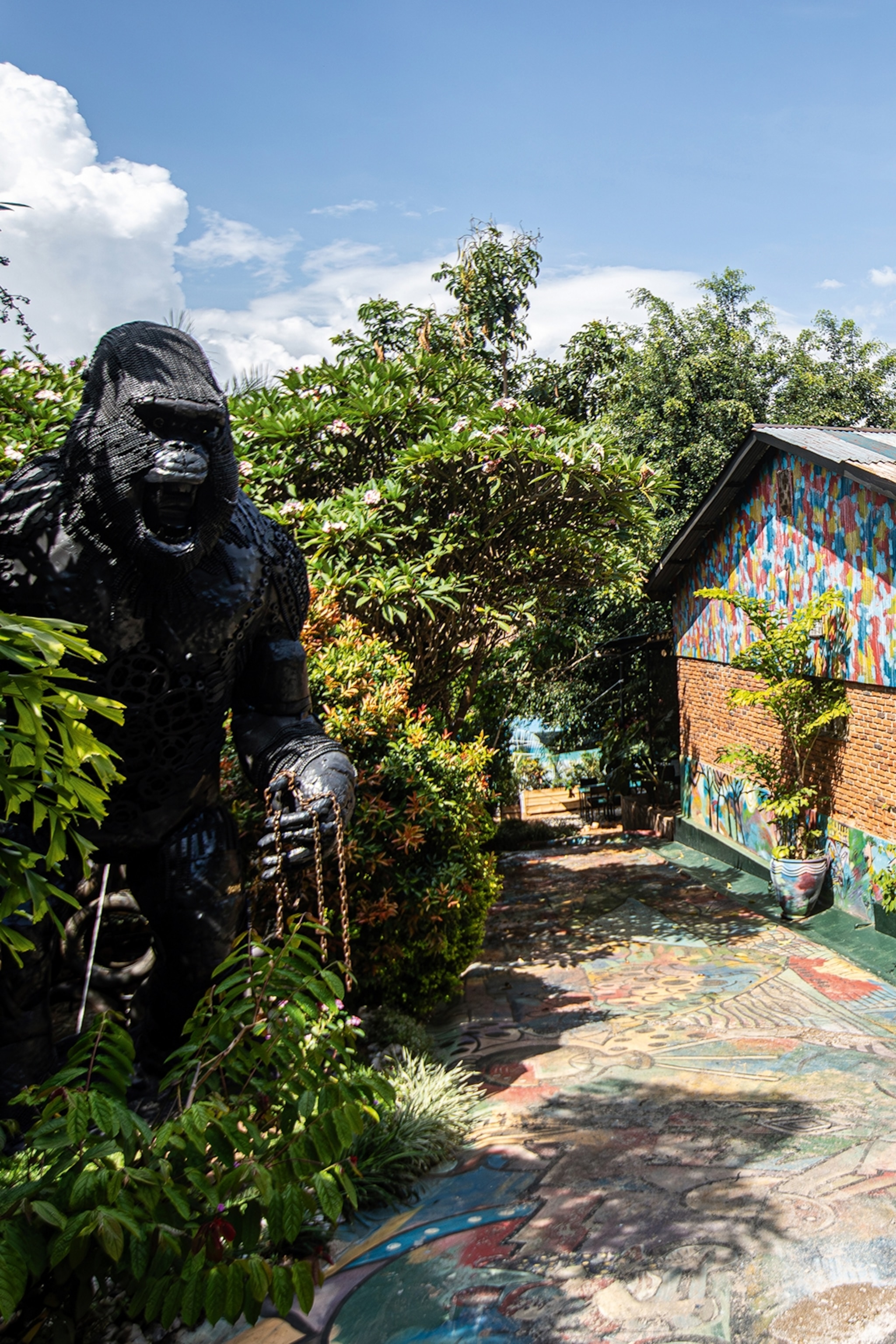 The exterior of a museum surrounded by forest with a massive gorilla sculpture overlooking the courtyard.