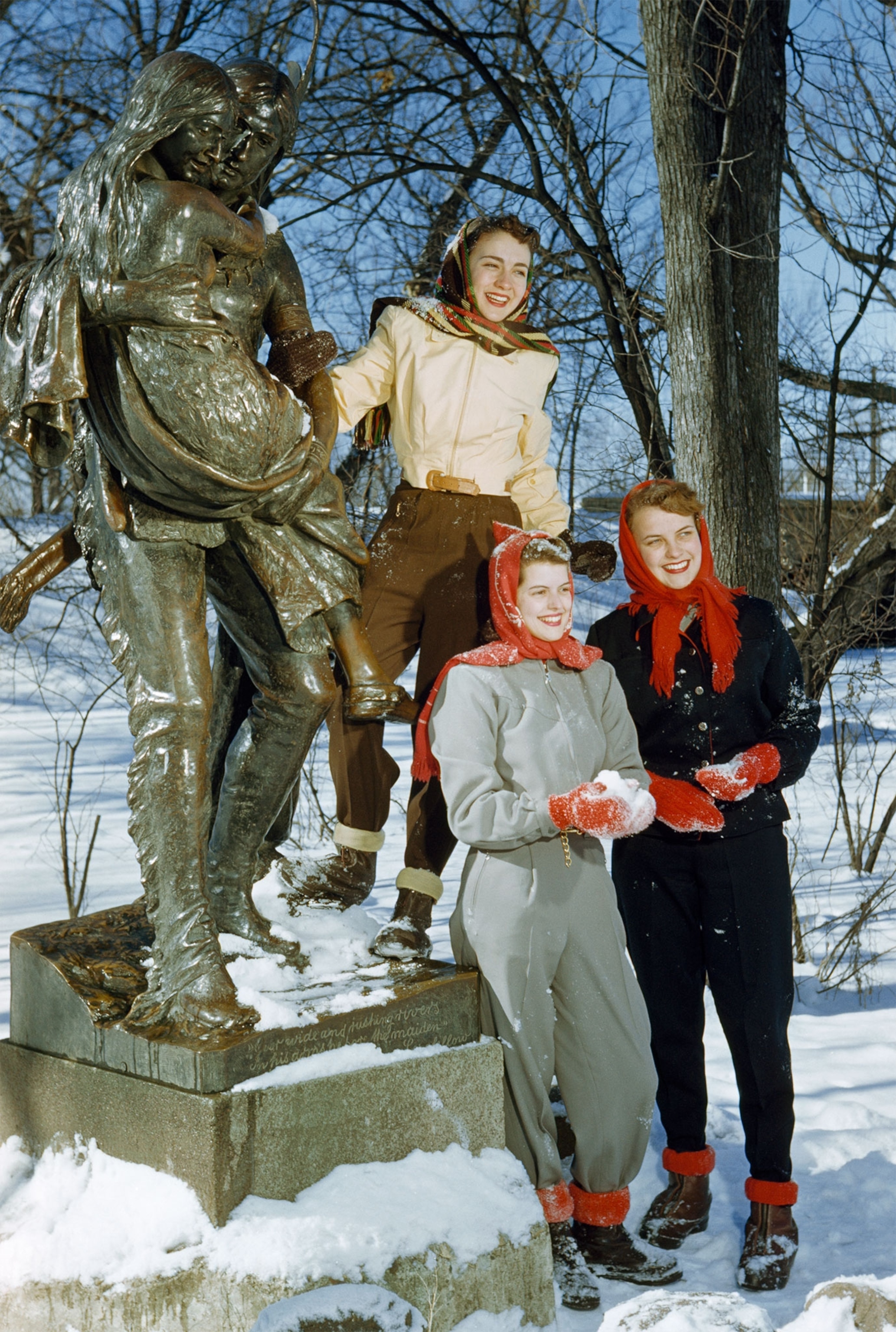 three women posing in front of a statue