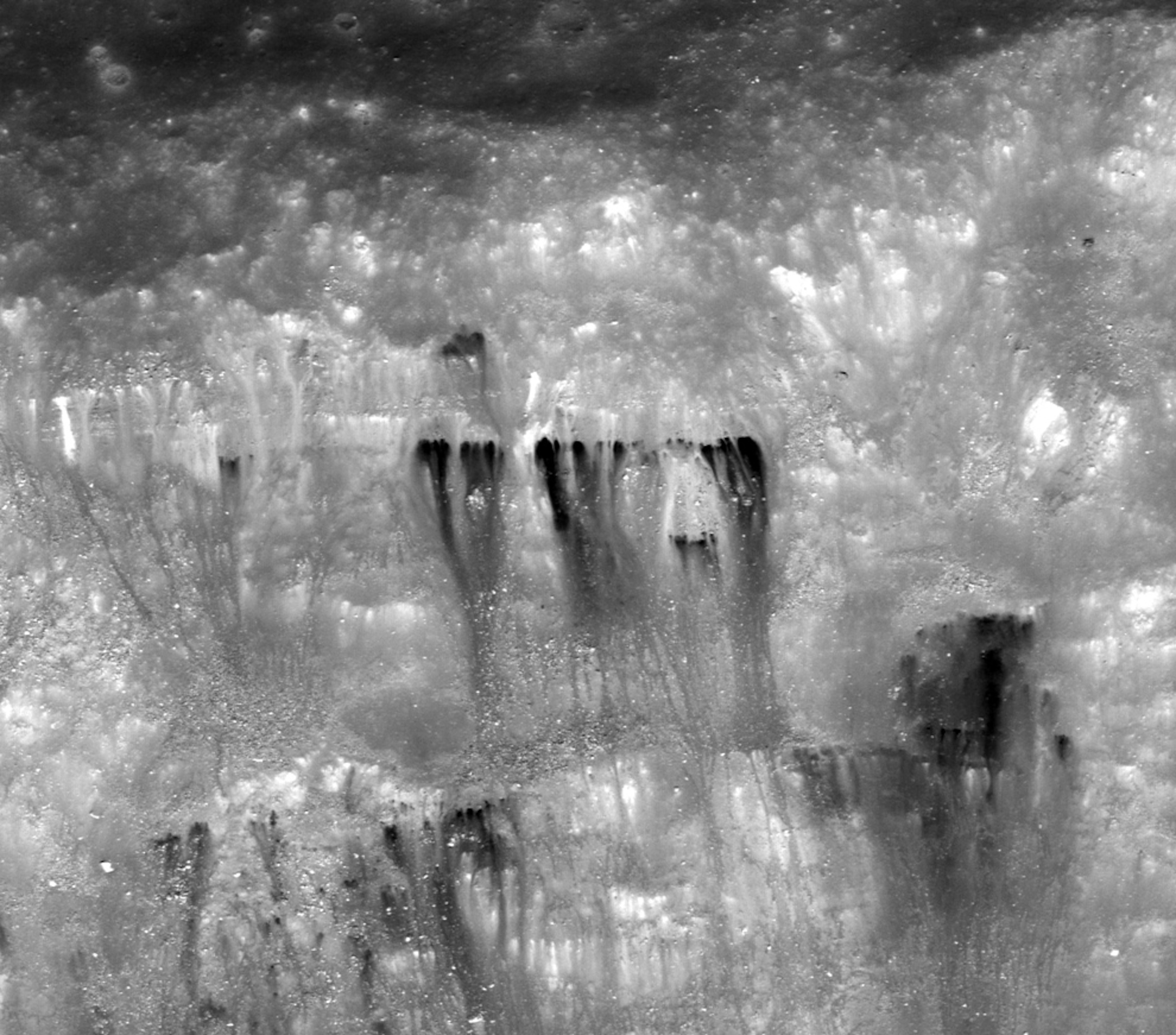 dark material flowing down the sides of a crater on the moon.