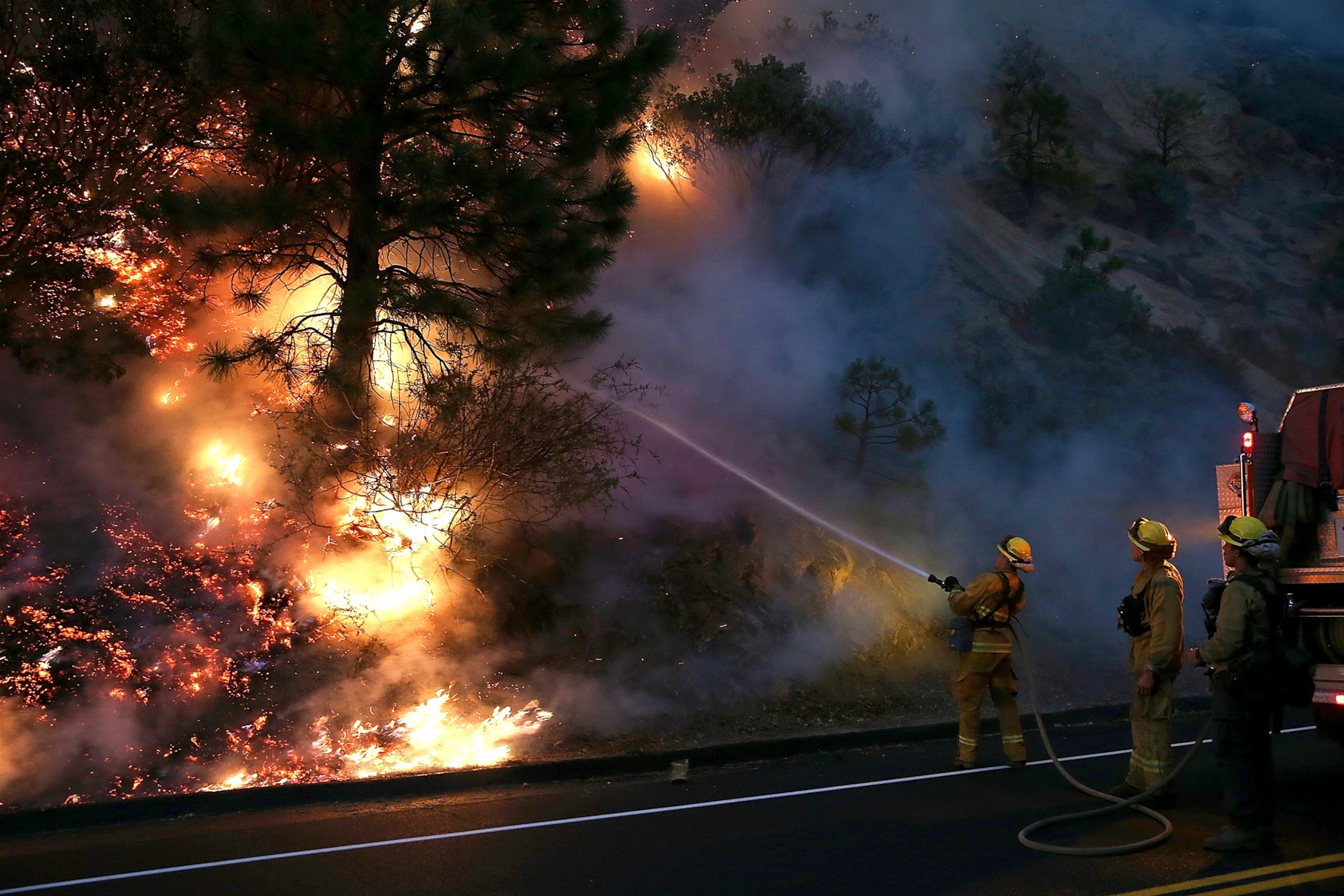 firefighters using a hose to douse flames from the Rim Fire