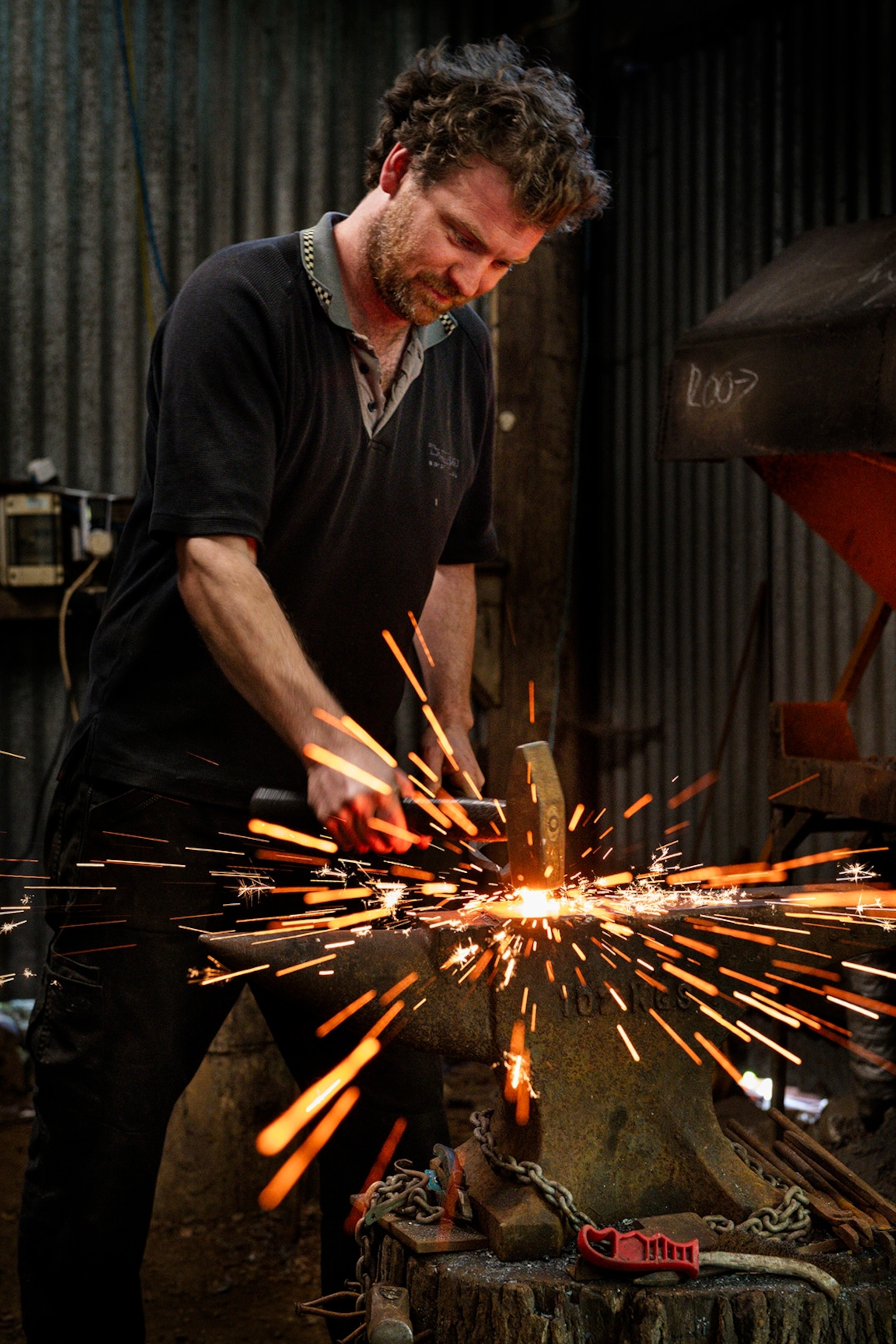 A young man heating steel on a workbench with sparks flying like fireworks.