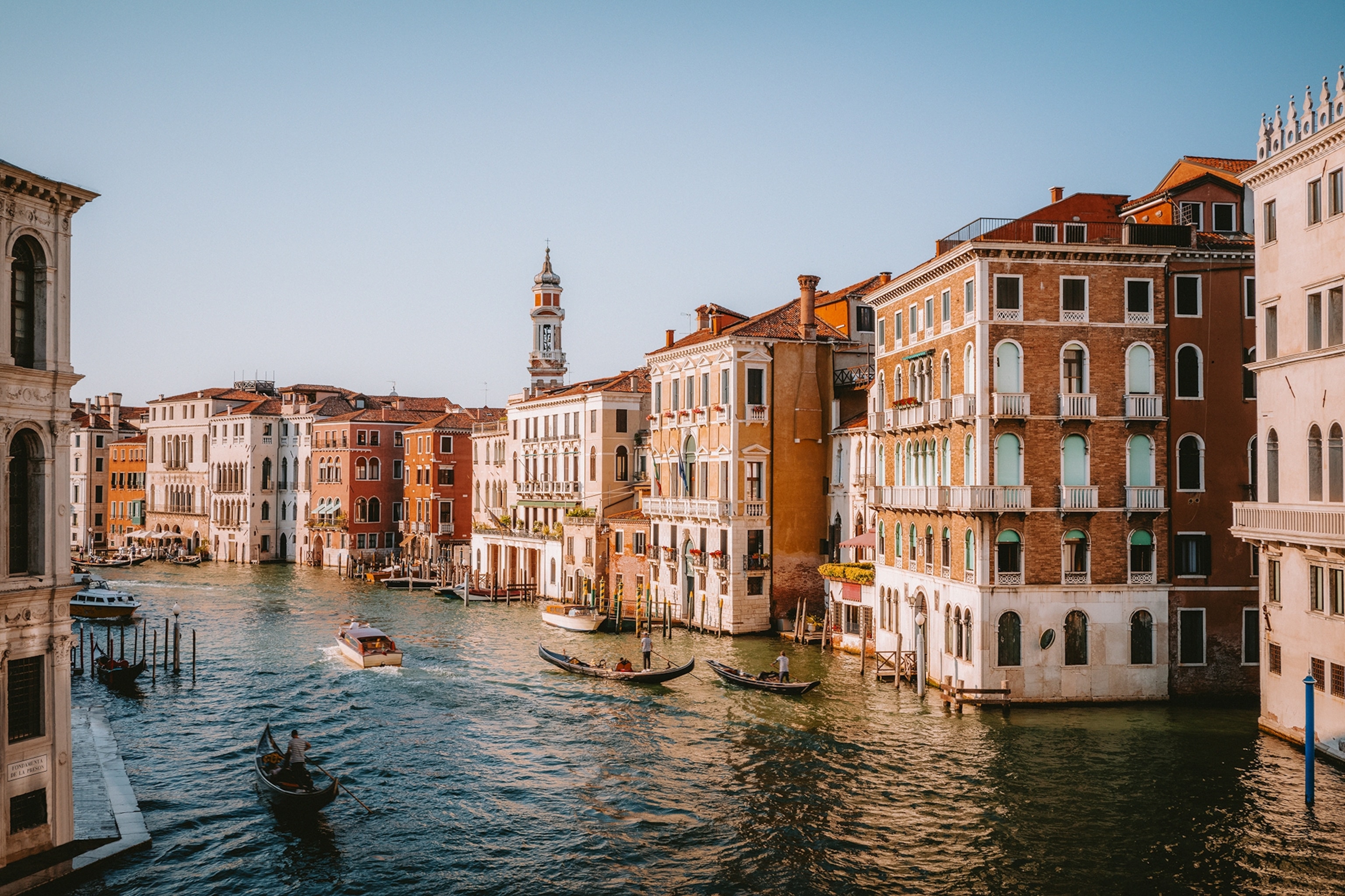 A wide canal running through the ancient city of Venice with gondola boats.