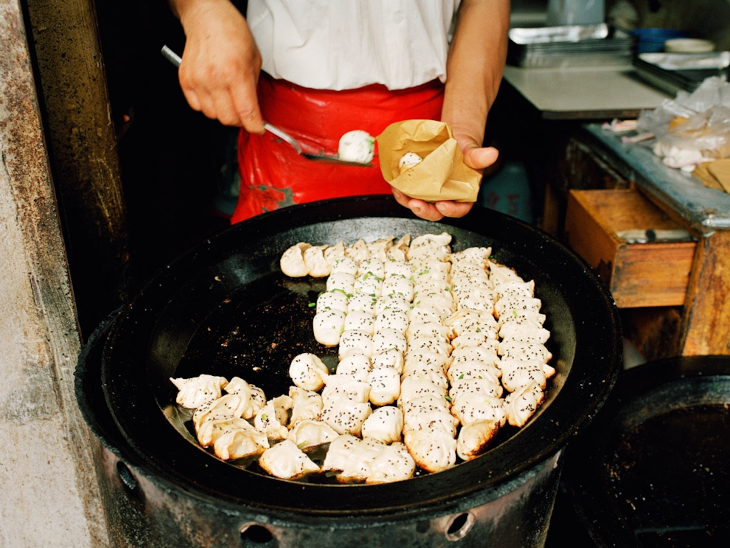 Vendor spooning dumplings from a large pan