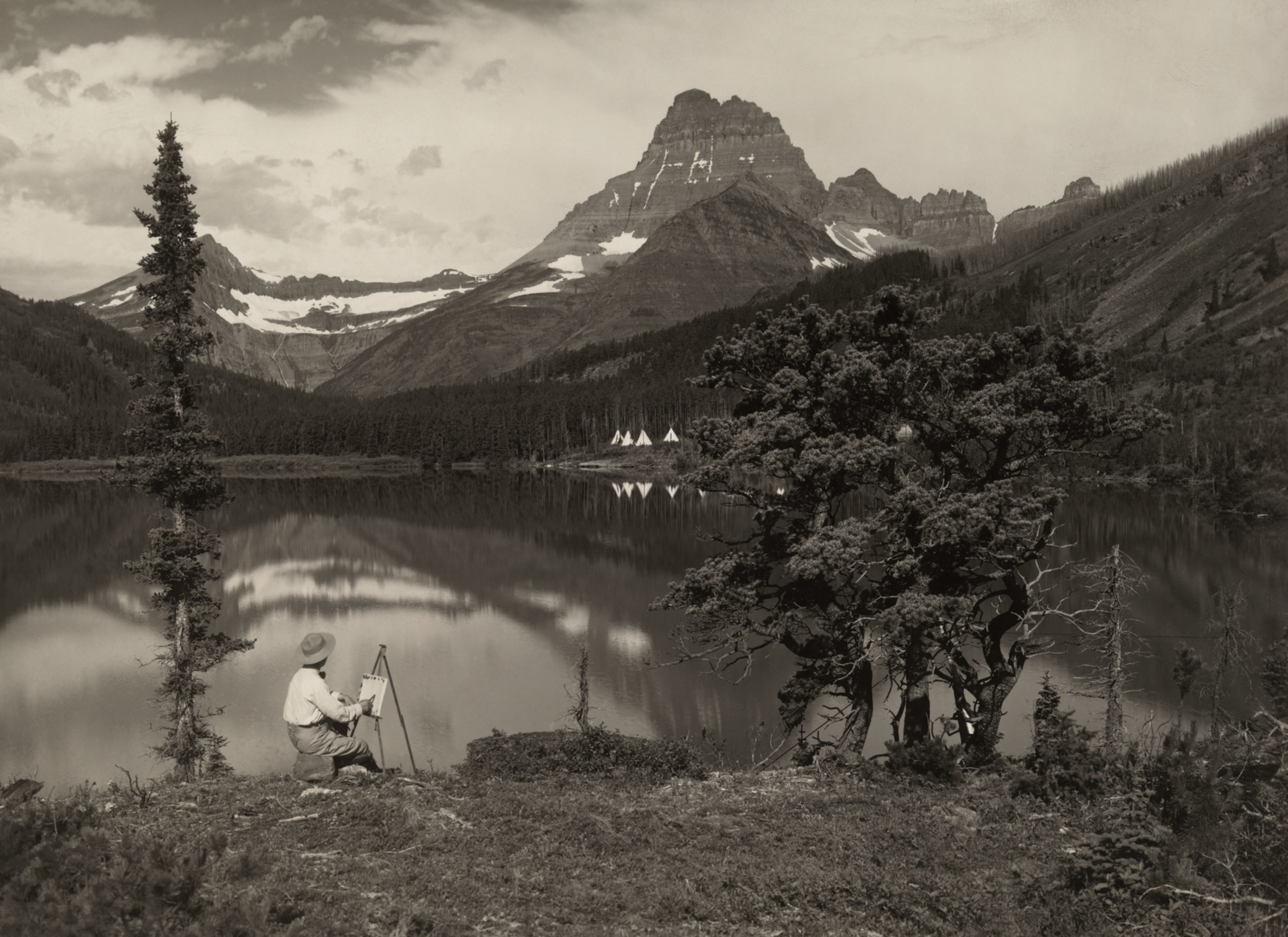 A man paints the beauties of Glacier National Park on a canvas.