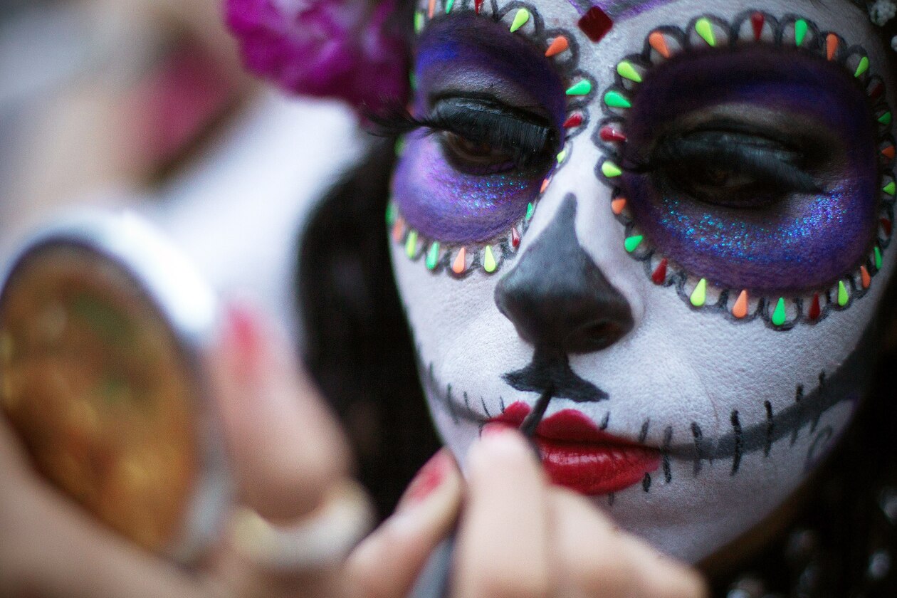 a woman applying makeup for Day of the Dead, Mexico