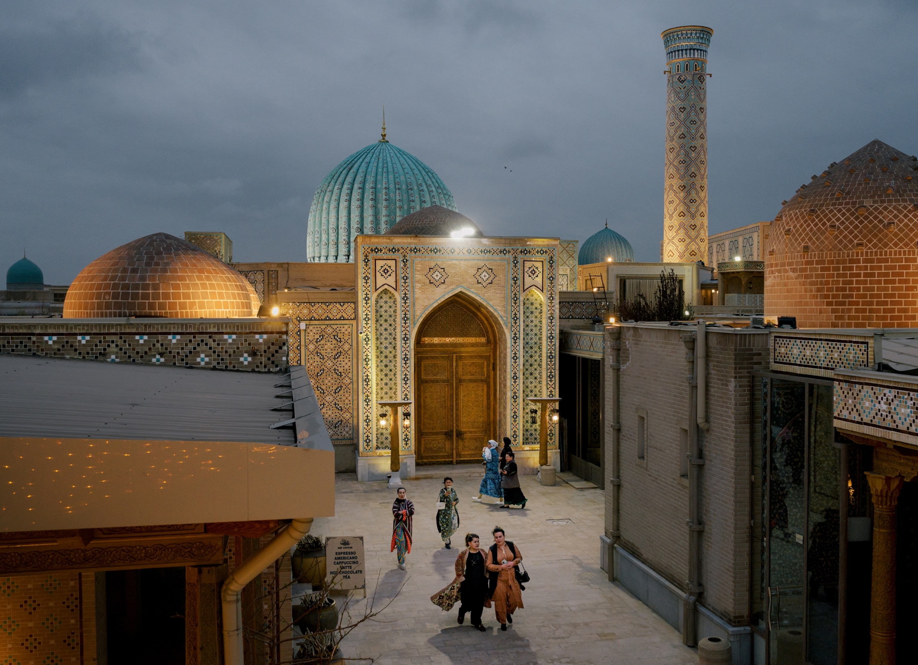 Sidewalk in a city with intricately tiled buildings with arches, columns, and various designs.