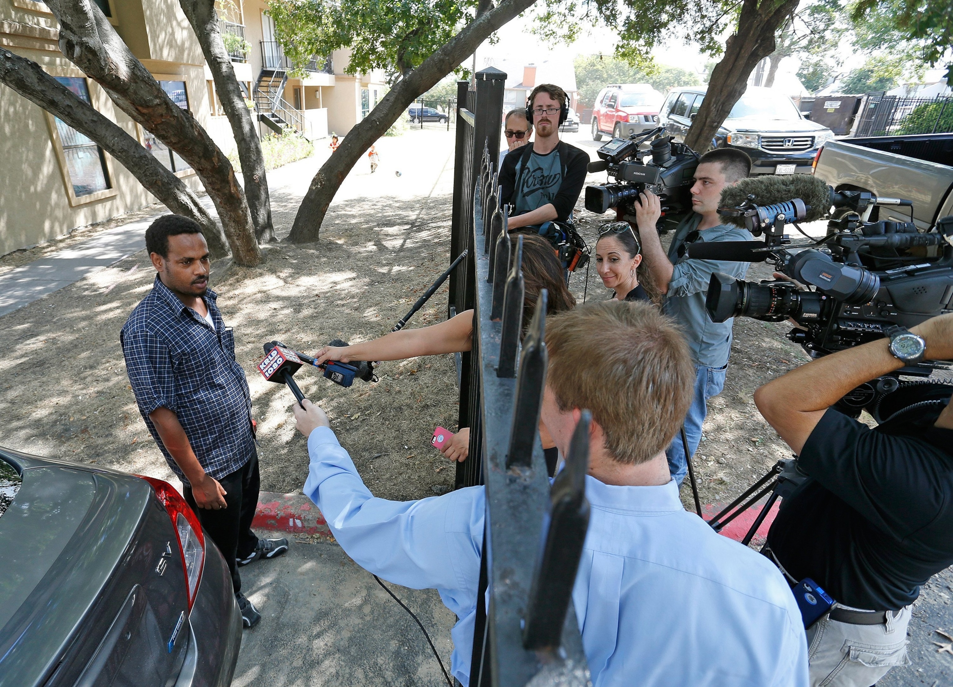 a man talking to the news media gathered at the fence of the Ivy Apartments.