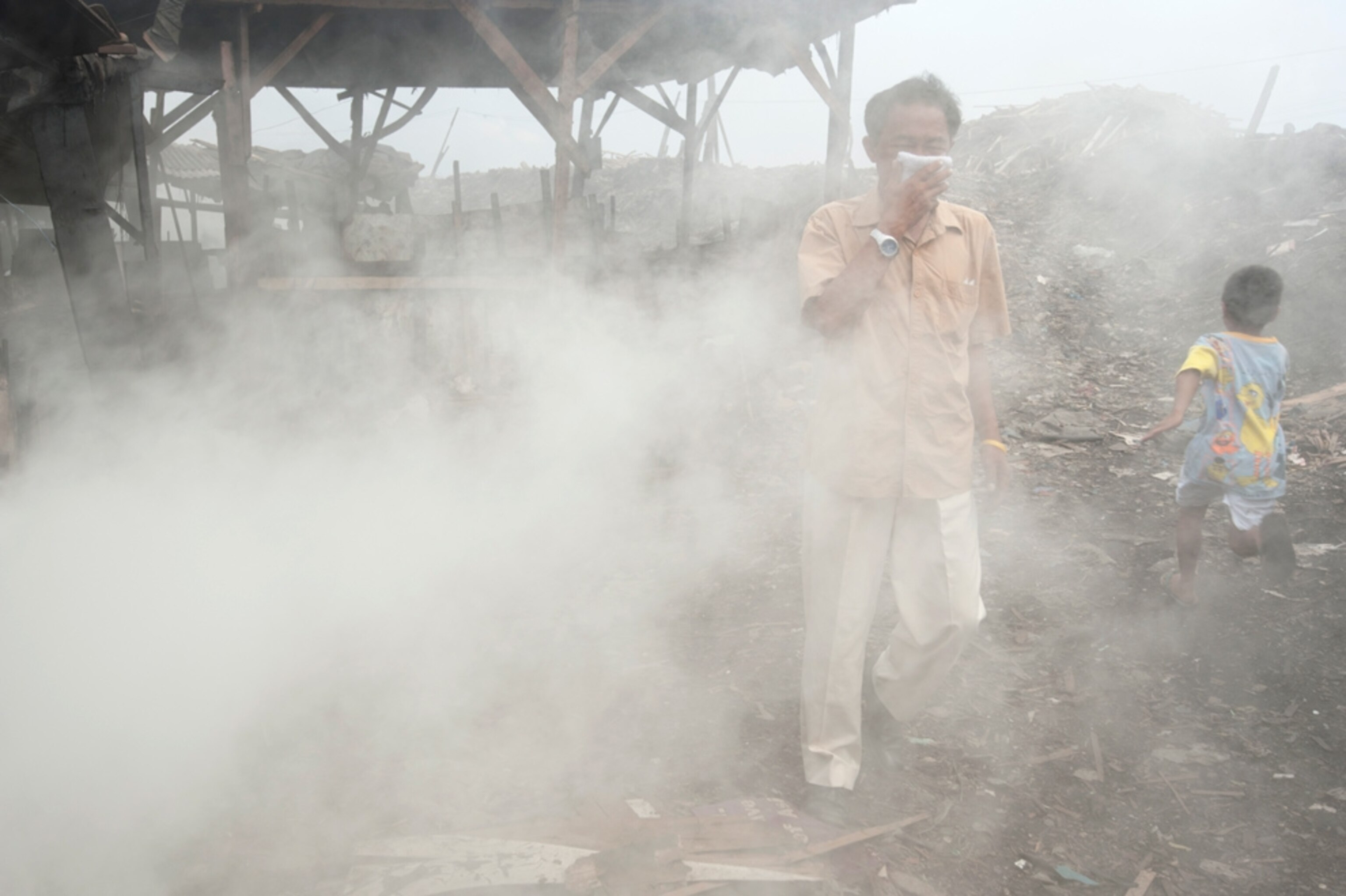 A man walks between charcoal-burning pits, Manila