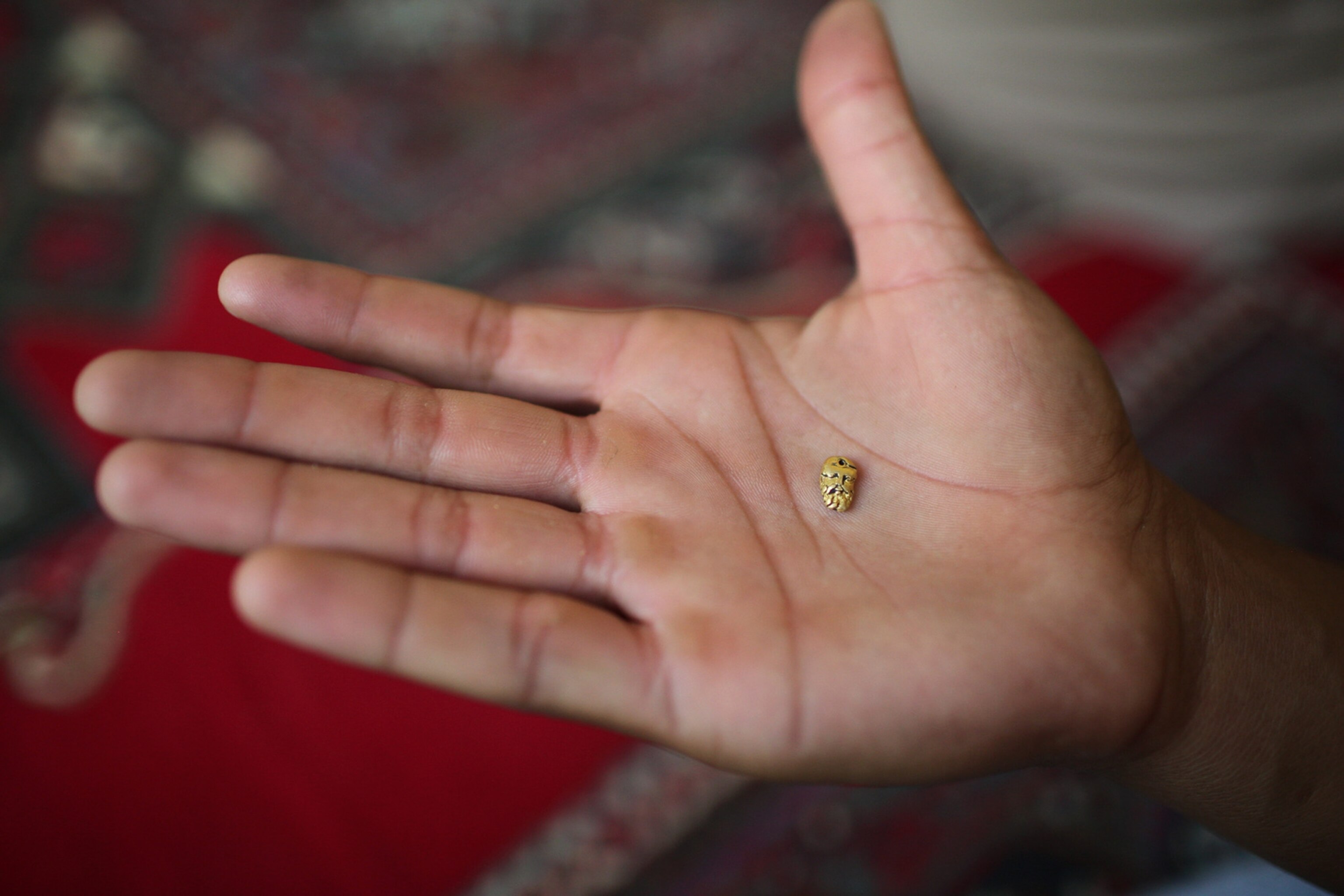a hand holding a small antique golden head from Afghanistan