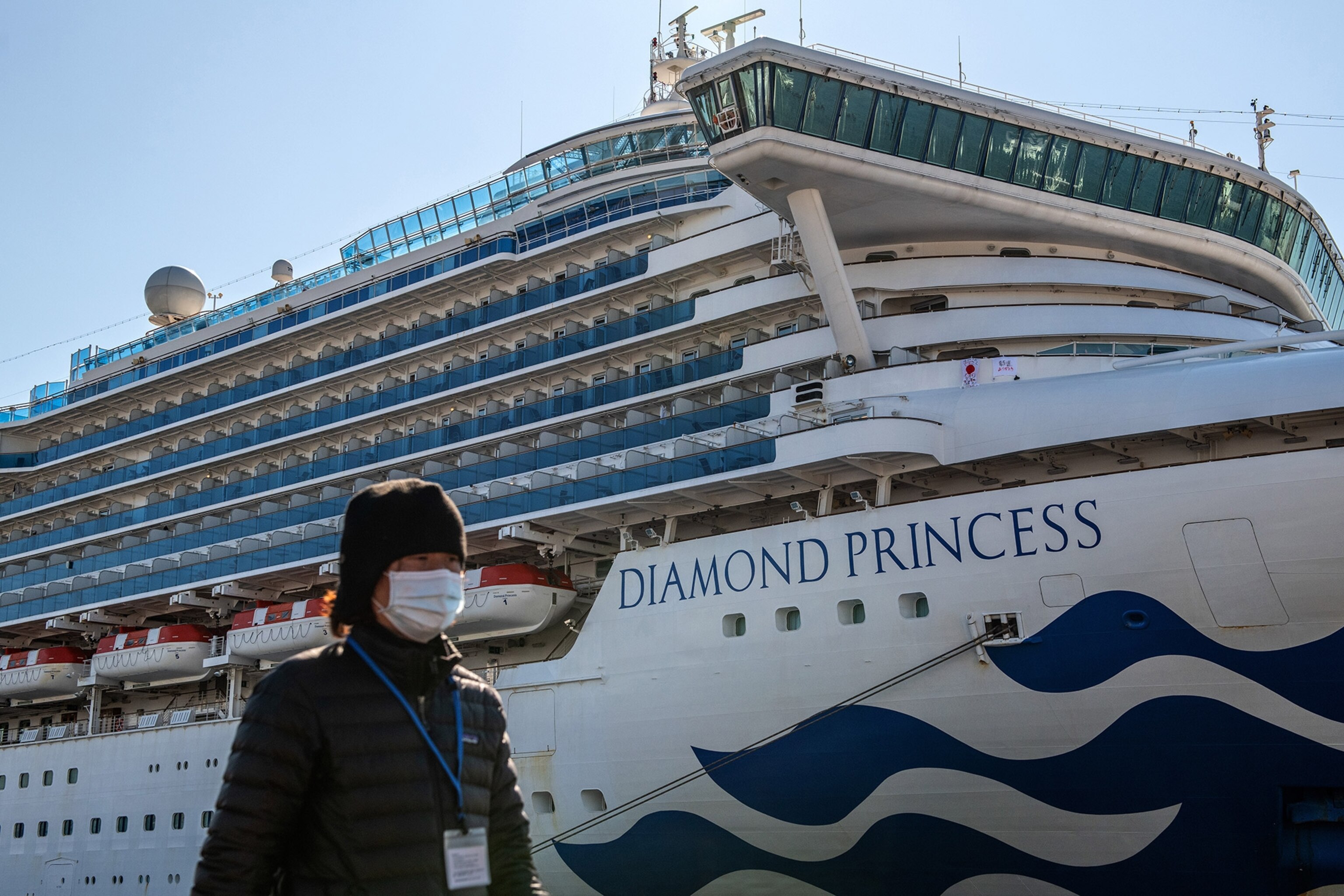 a person walking past a cruise ship docked and quarantined for coronavirus cases in Japan