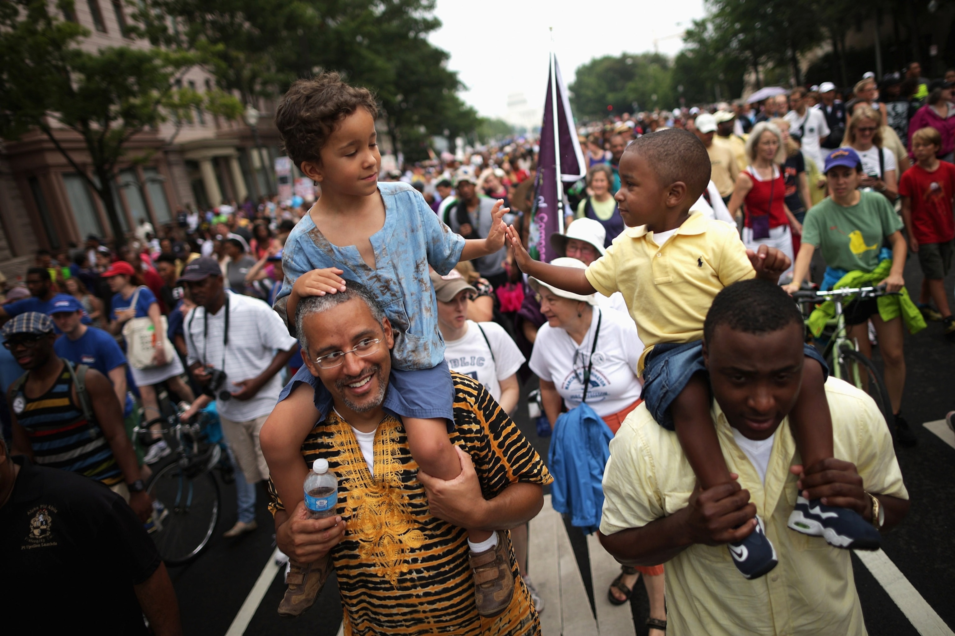 WASHINGTON, DC - AUGUST 28: (L-R) John Mbugua and his son Giovanni Mbugua, 6, of San Jose, California, and Lavon Johnson and his son Mason Johnson, 2, of Fort Meade Maryland, greet one another while marching with thousands of other people from Capitol Hill to the Lincoln Memorial during the 'Let Freedom Ring Commemoration and Call to Action' honoring the 50th anniversary of the historic March on Washington for Jobs and Freedom August 28, 2013 in Washington, DC. The 1963 landmark civil rights event was where Dr. Martin Luther King Jr. delivered his famous speech, saying, 'I still have a dream, a dream deeply rooted in the American dream...one day this nation will rise up and live up to its creed, "We hold these truths to be self evident: that all men are created equal." I have a dream . . .' (Photo by Chip Somodevilla/Getty Images)