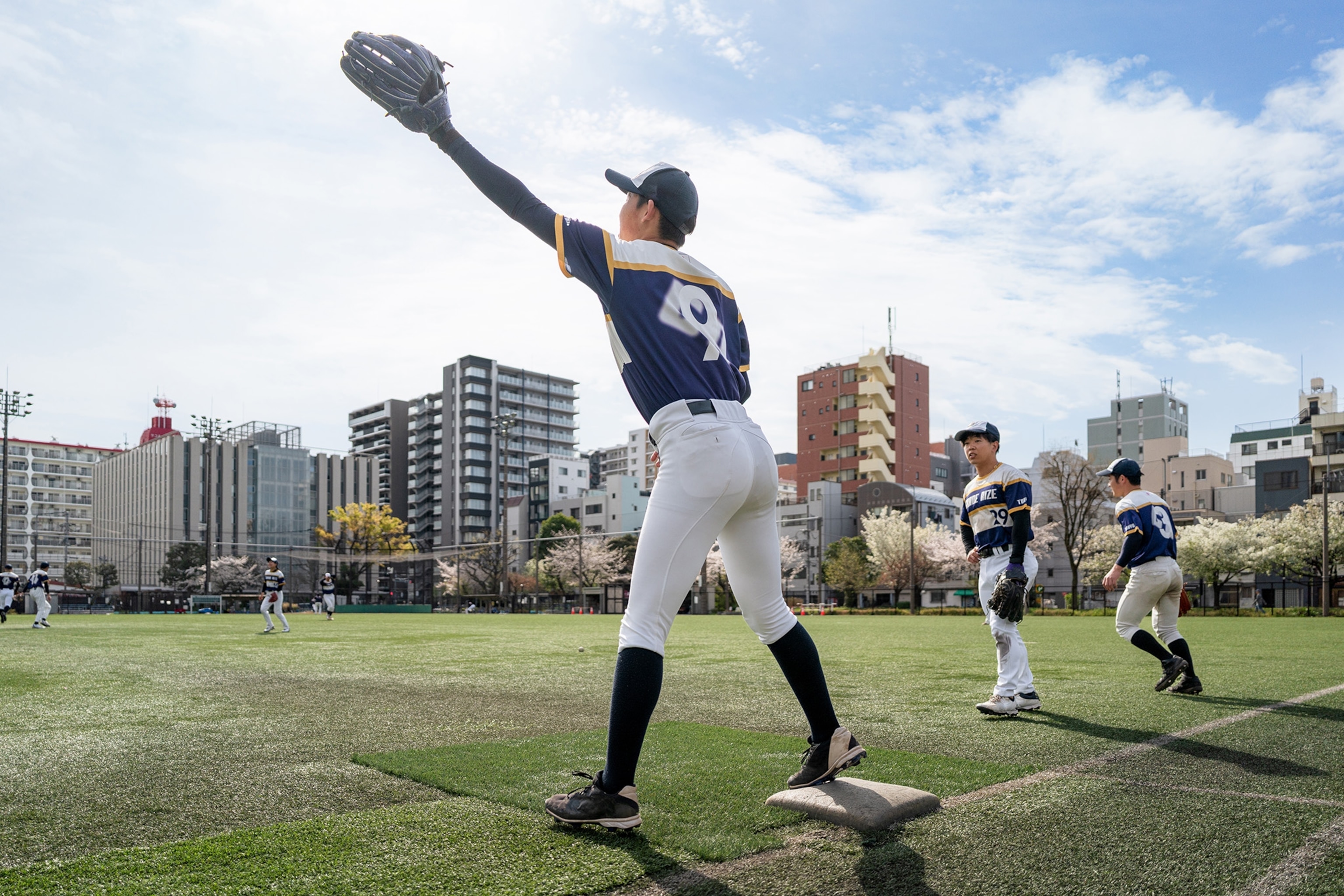 A baseball player aiming to catch a ball on the pitch.