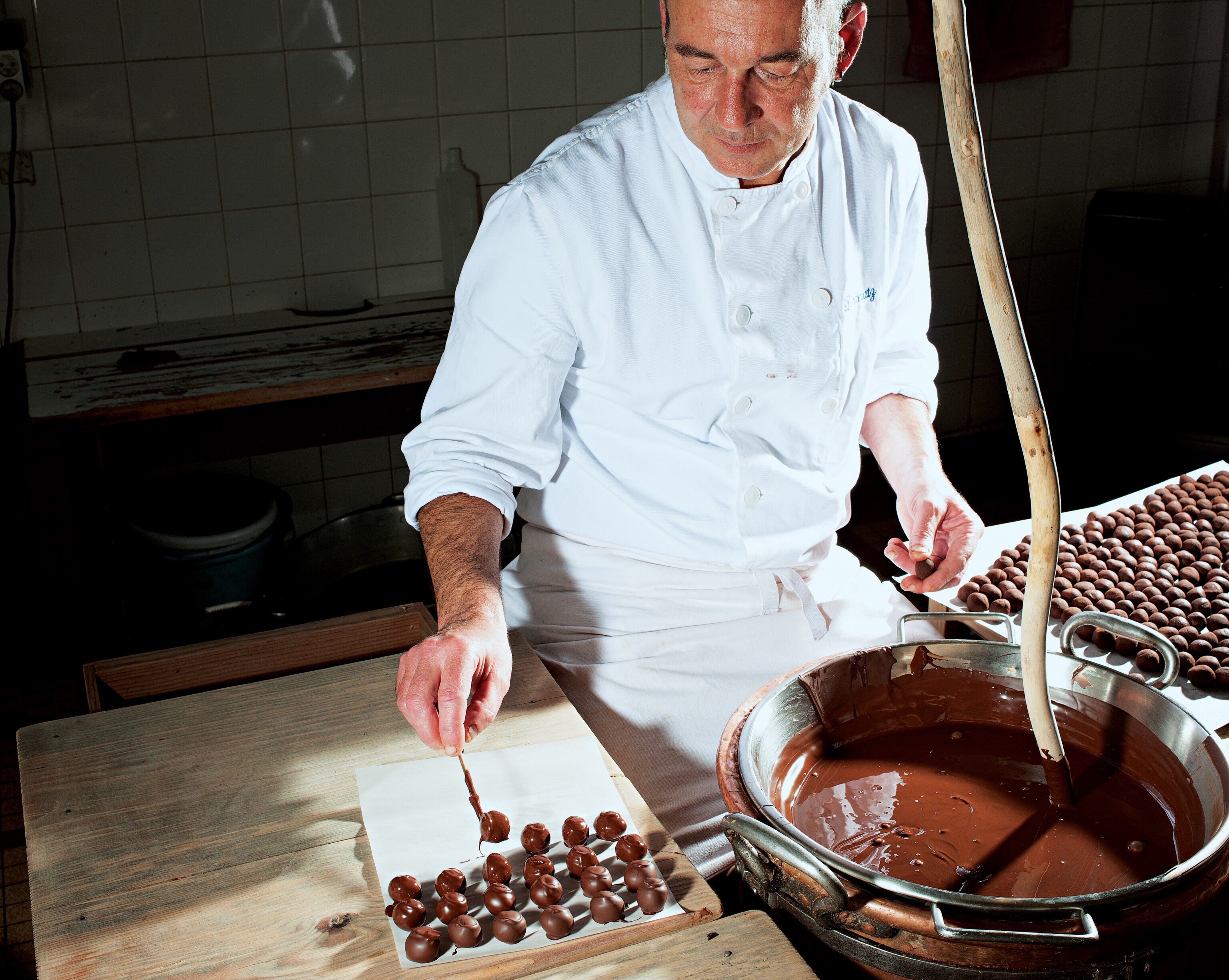 master chocolatier Denis Ortali dipping ganache into chocolate at Daranatz in Bayonne