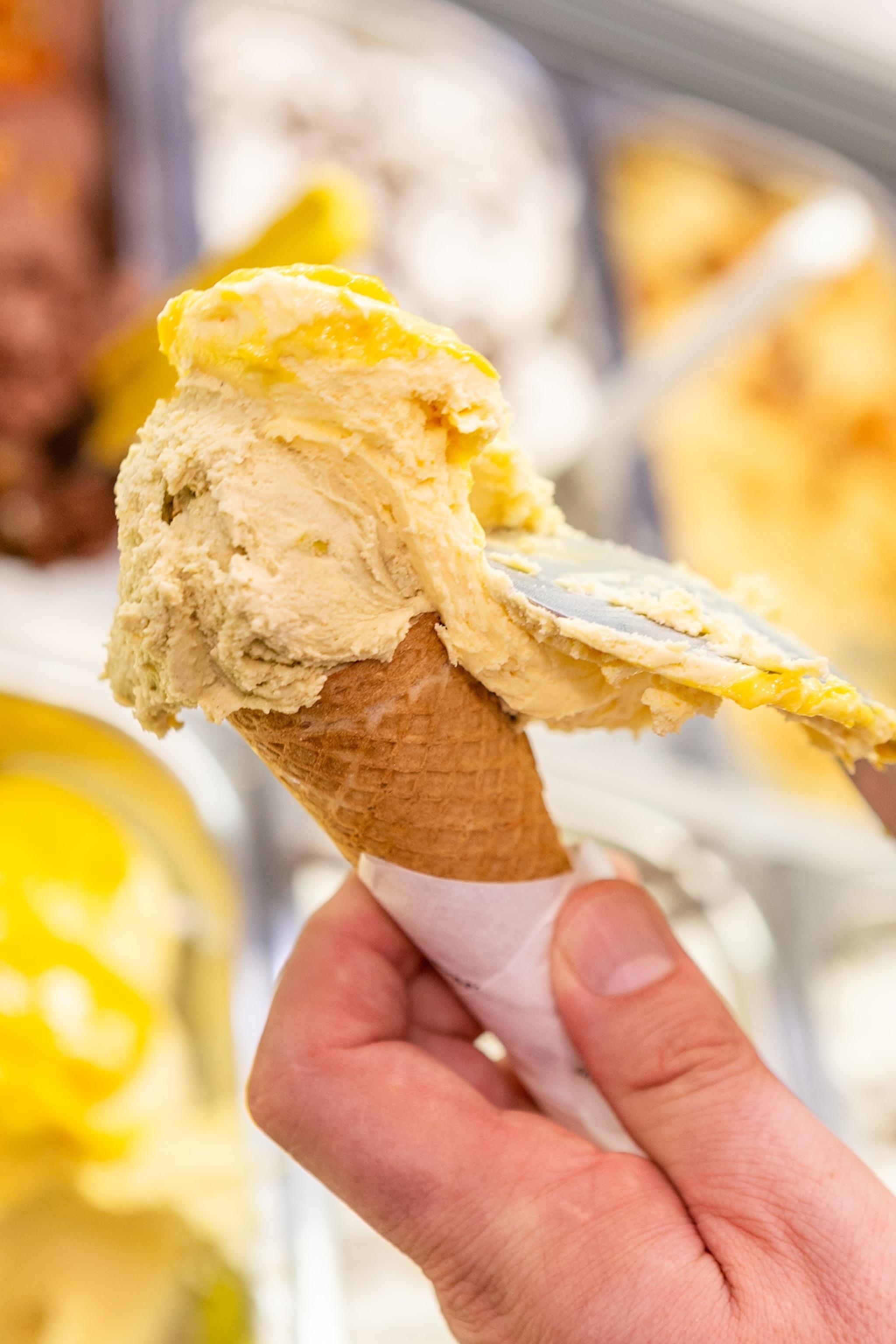 a server at Gunther adds a rich scoop of gelato to a waffle cone