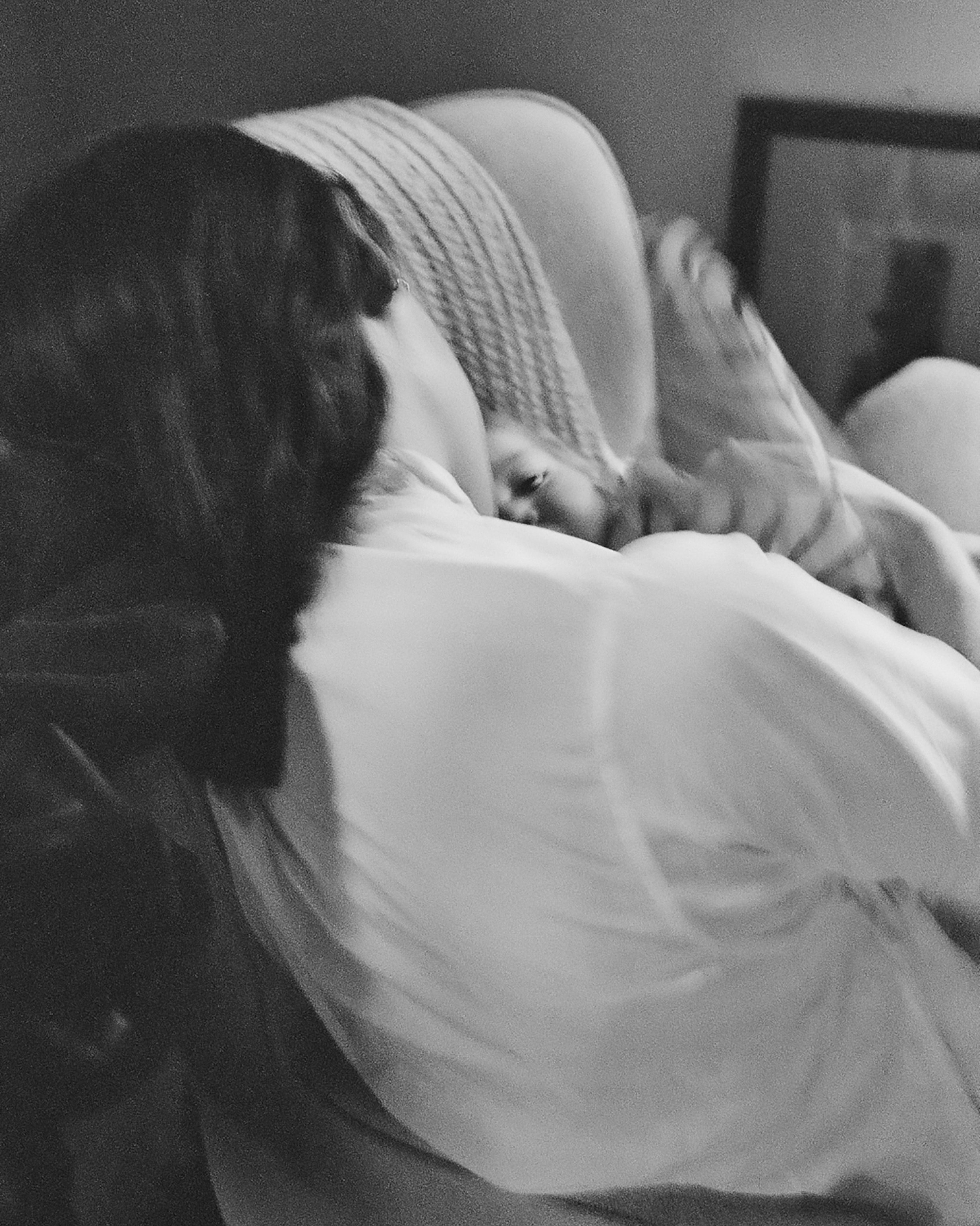 The back of a woman holding a baby in a chair.