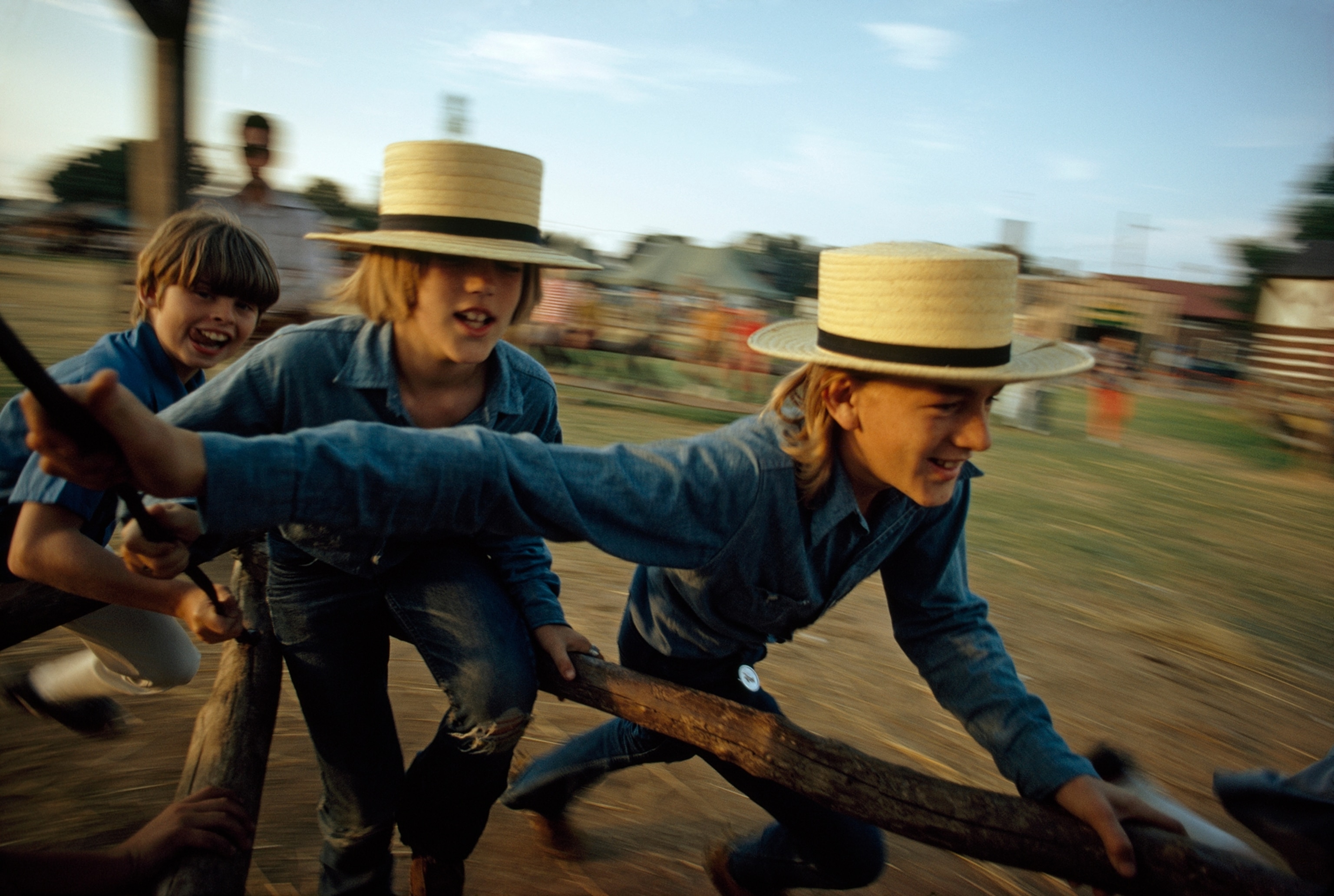 Boys in Amish hats turn an antique farm machine into a merry-go-round in Kutztown, Pa.