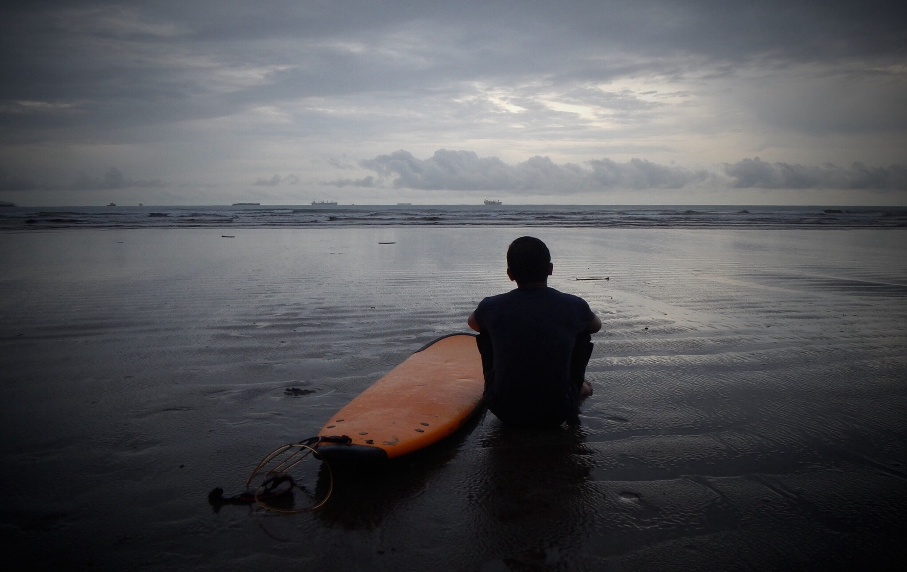 a person looking out across the water with surfboard