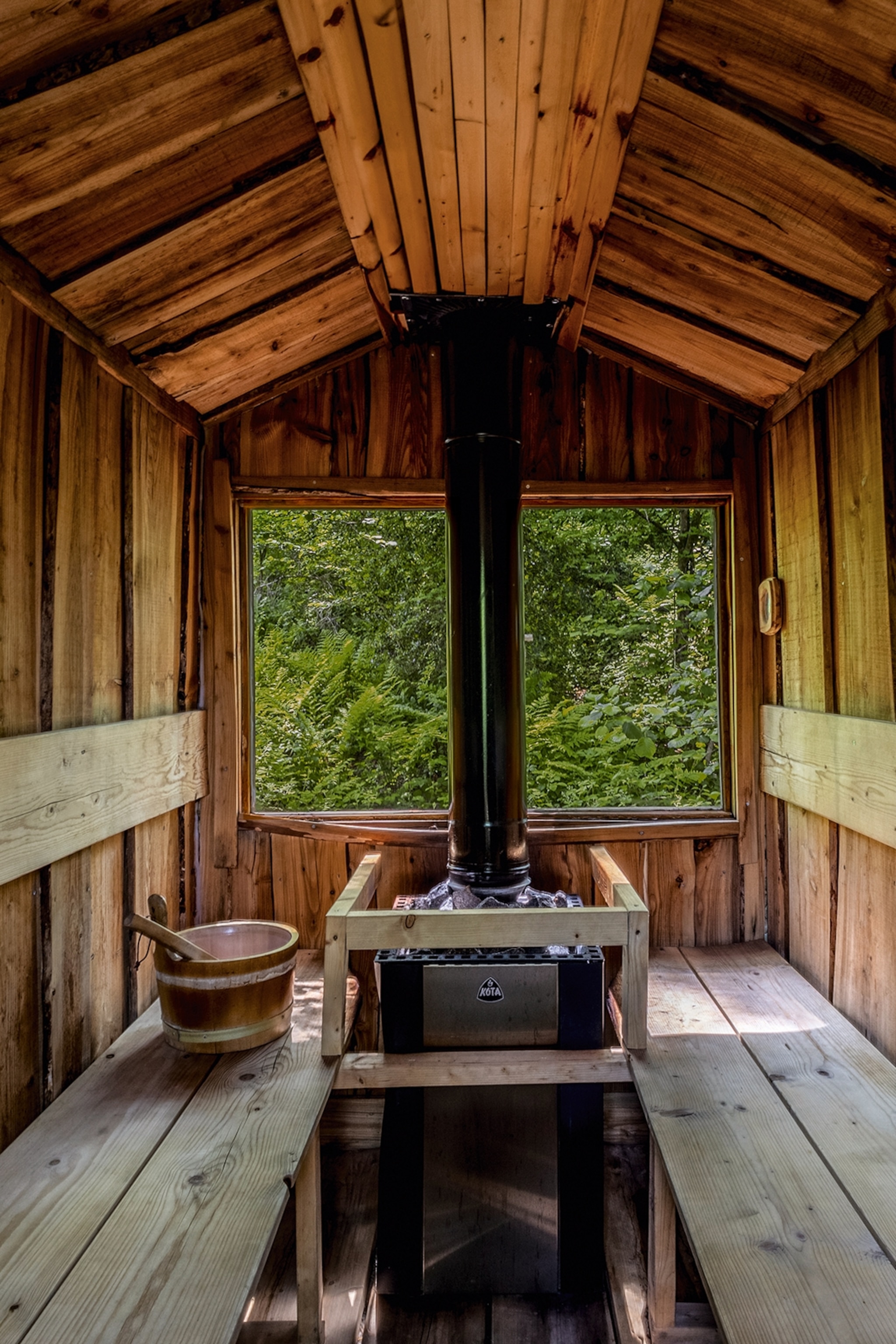 The interiors of a wooden sauna with views into a forest.