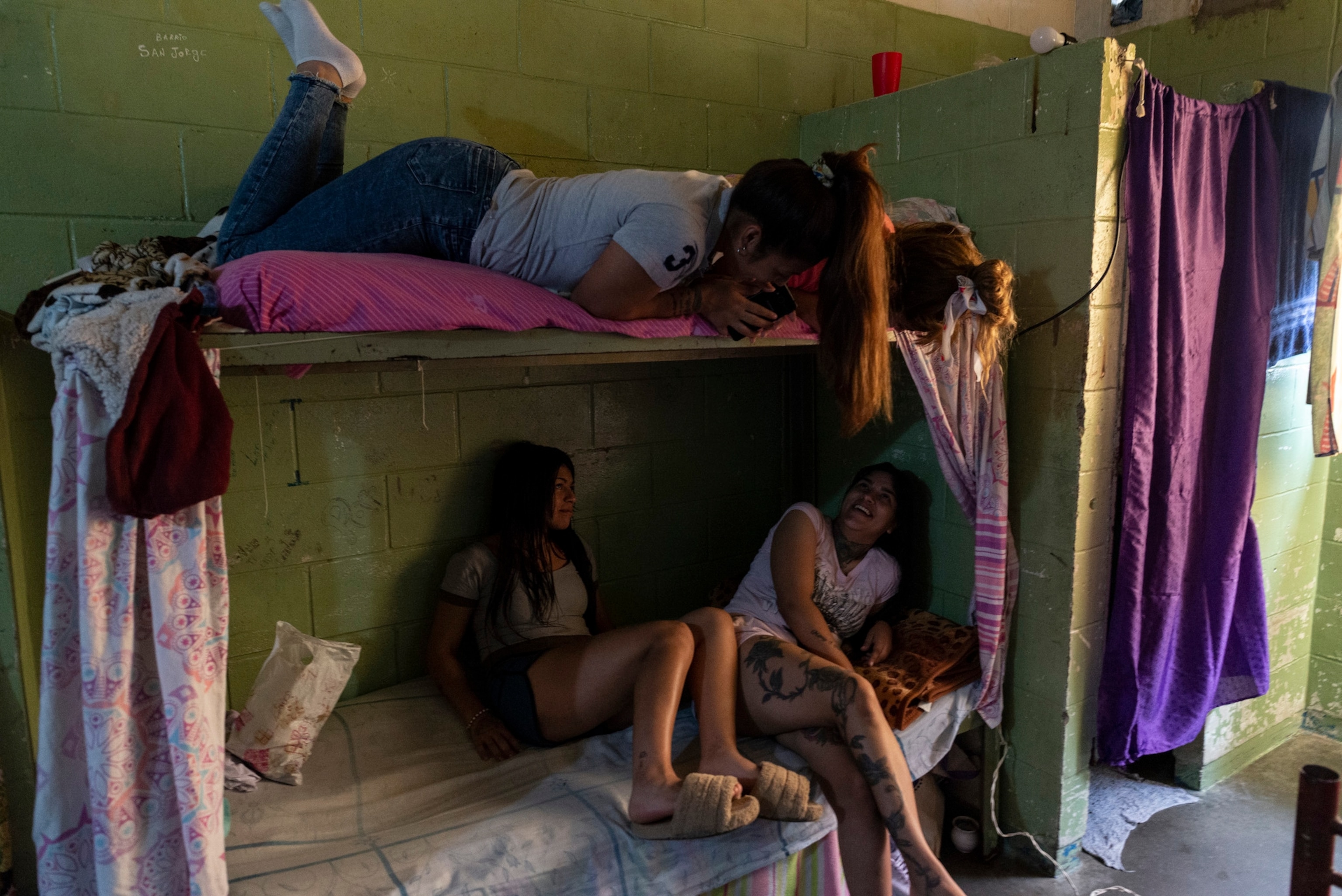 Two girls sit on the top bunk of a jail cell bunk bed, and two others sit on the bottom.