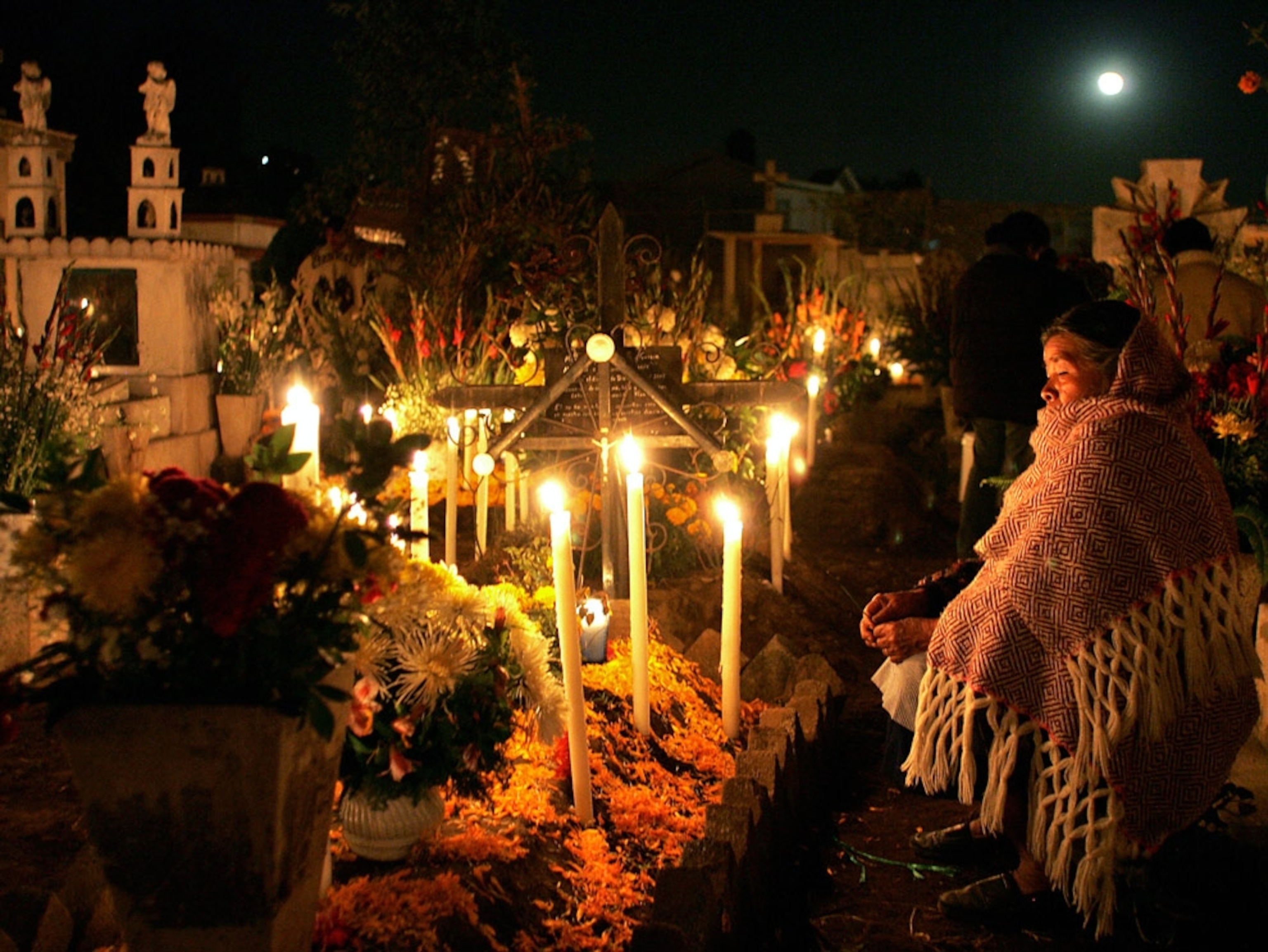 A woman praying in a candlelit cemetery