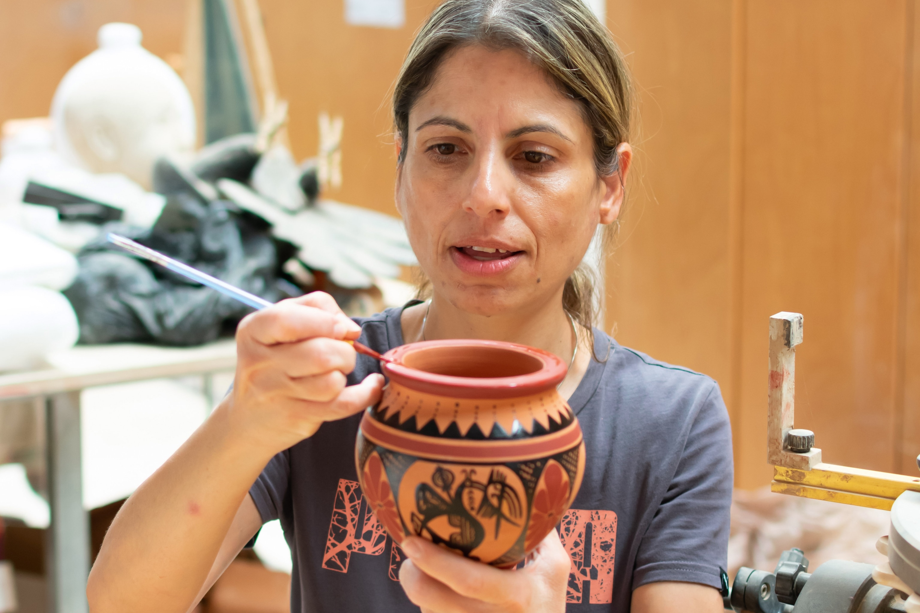 Artisanal red-clay pottery being painted by woman