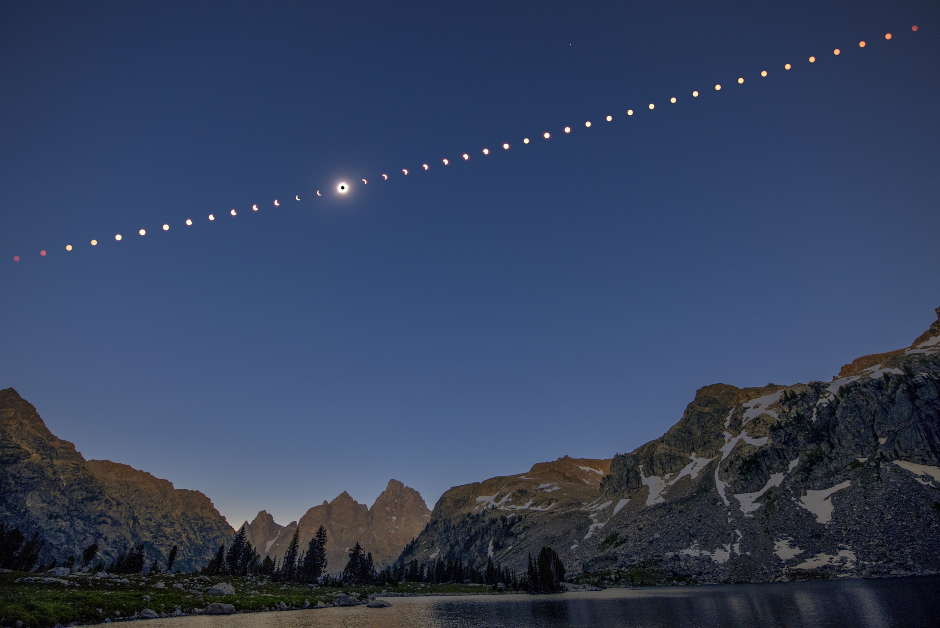 A composite sequence of a total solar eclipse over the Grand Teton mountains