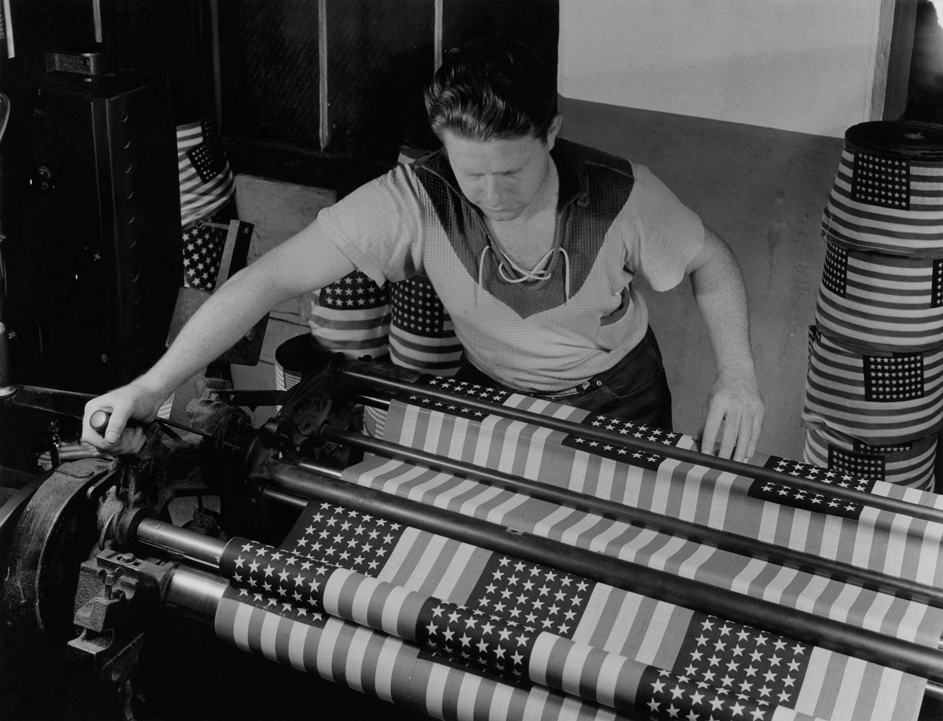 a factory worker using machinery to cut cotton American flags