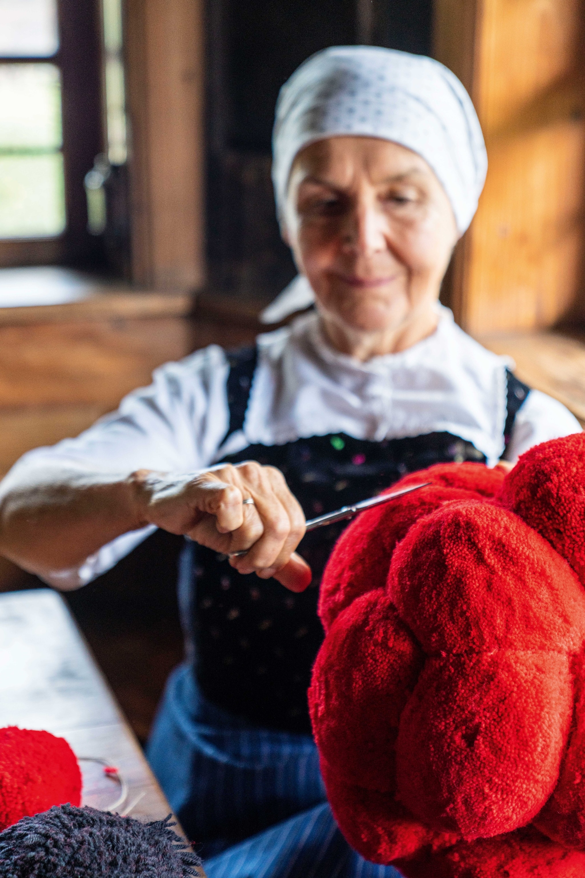 Balls of red wool are used in knitting by an old woman