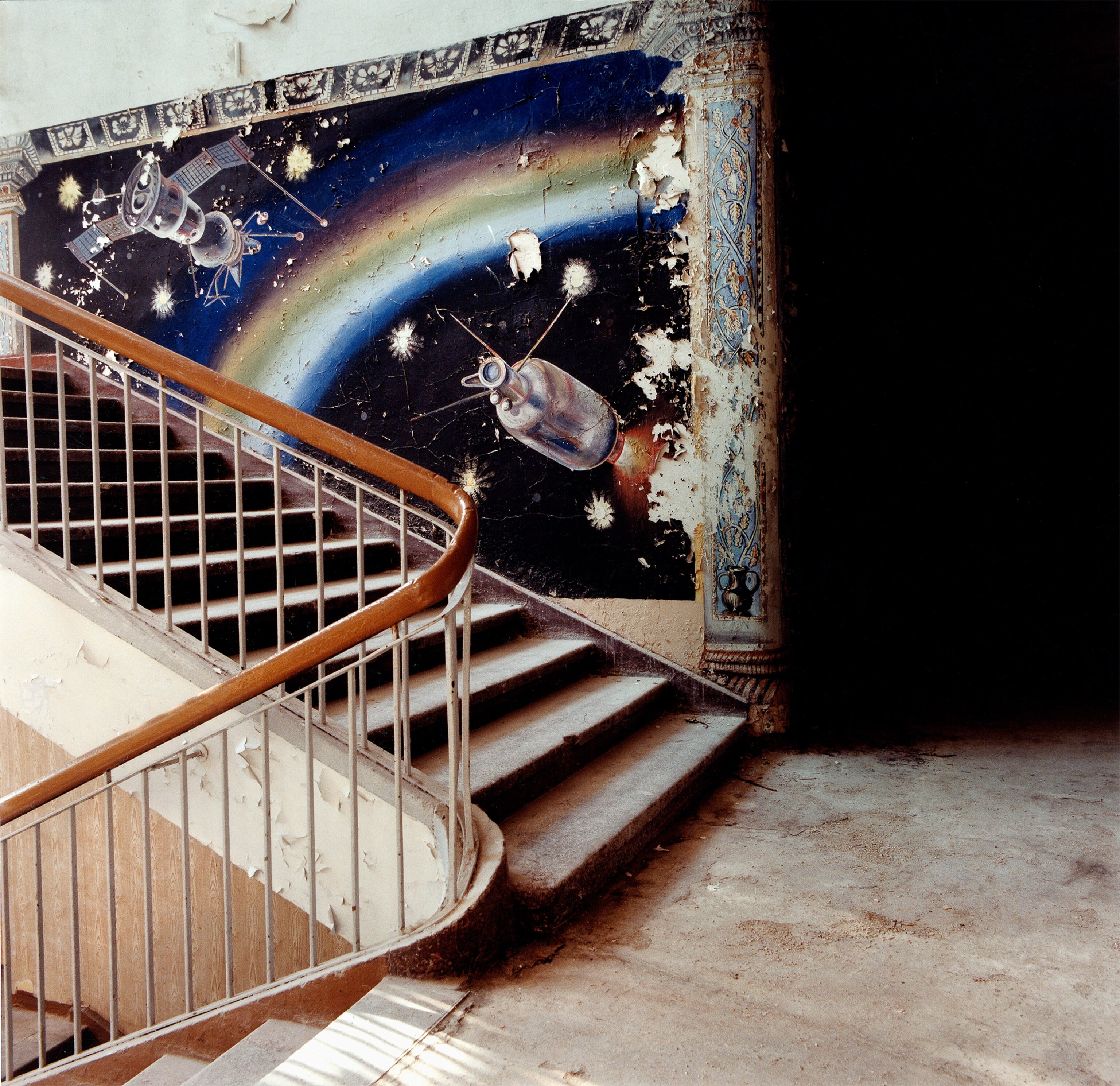 a painted mural of the Soviet spacecraft, the Sputnik, on a staircase in the former piloting school for the Soviet air force.