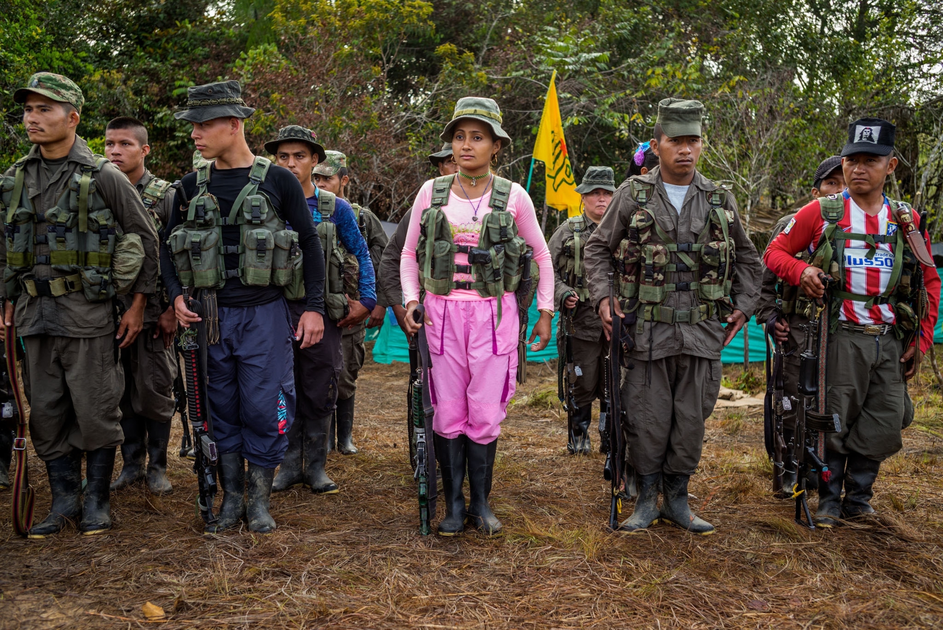 a group of soldiers standing at attention wearing casual clothes in the jungle