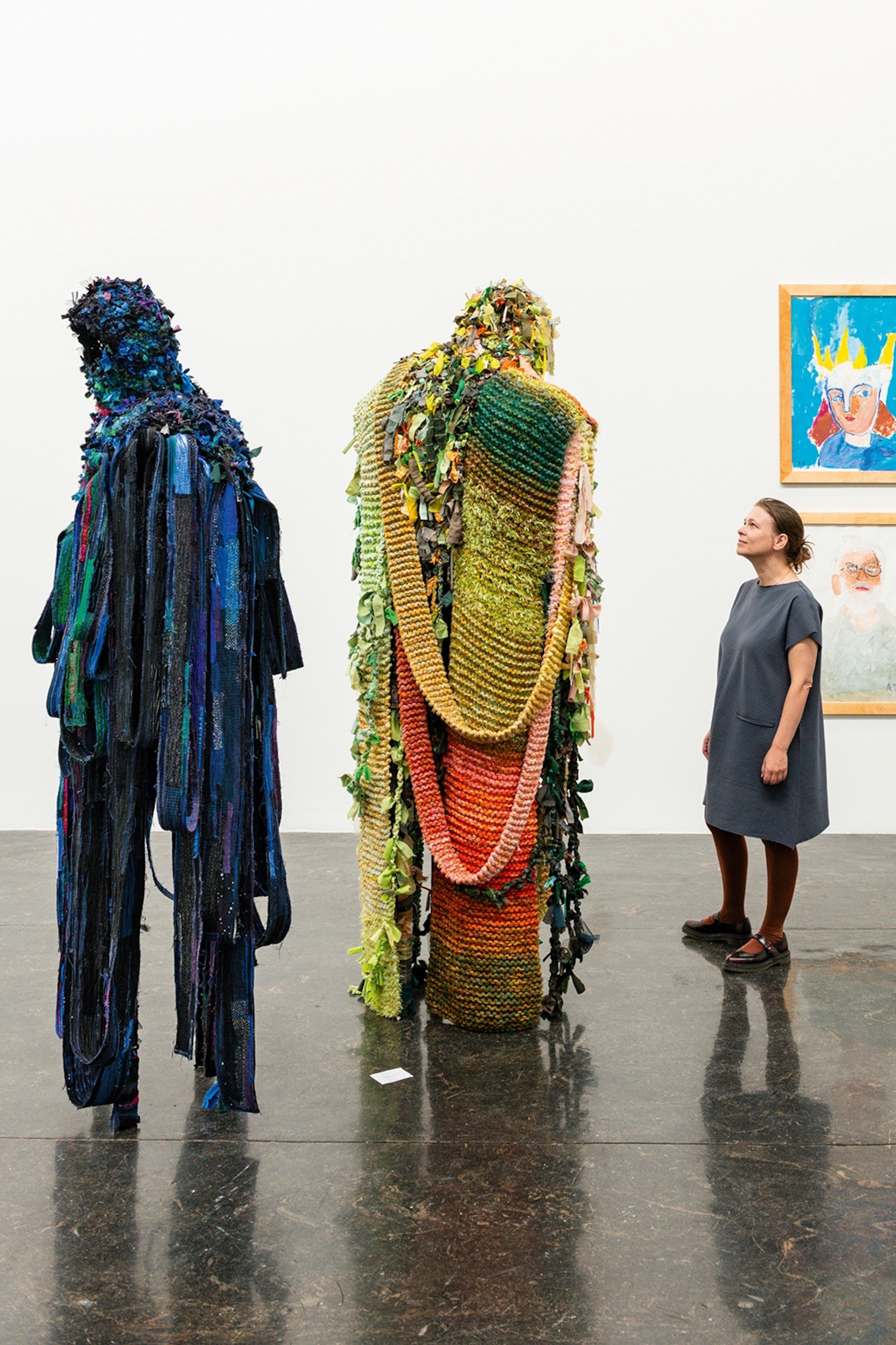 A woman looks up at two art pieces in a gallery.