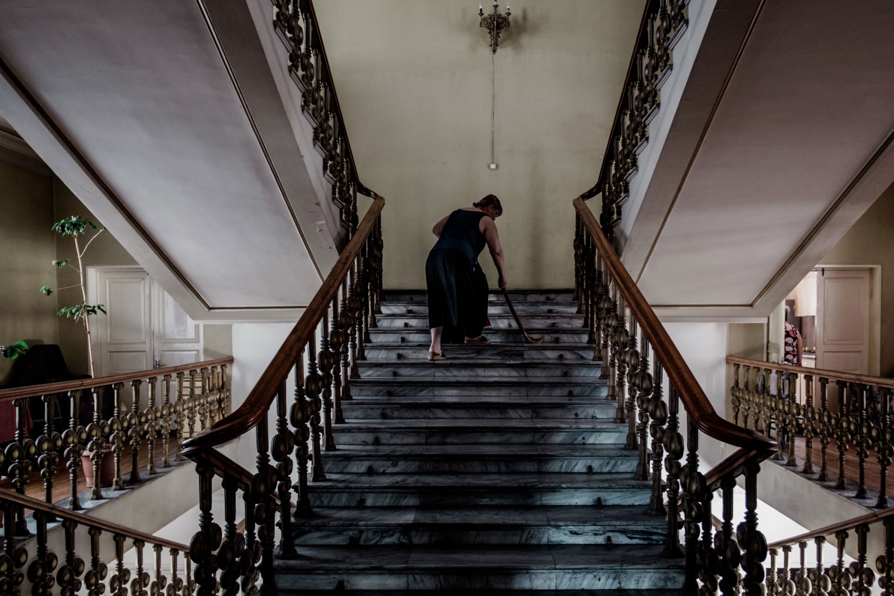 Nana, 58, from Sukhumi, Abkhazia mops the stairs of Hotel Georgia