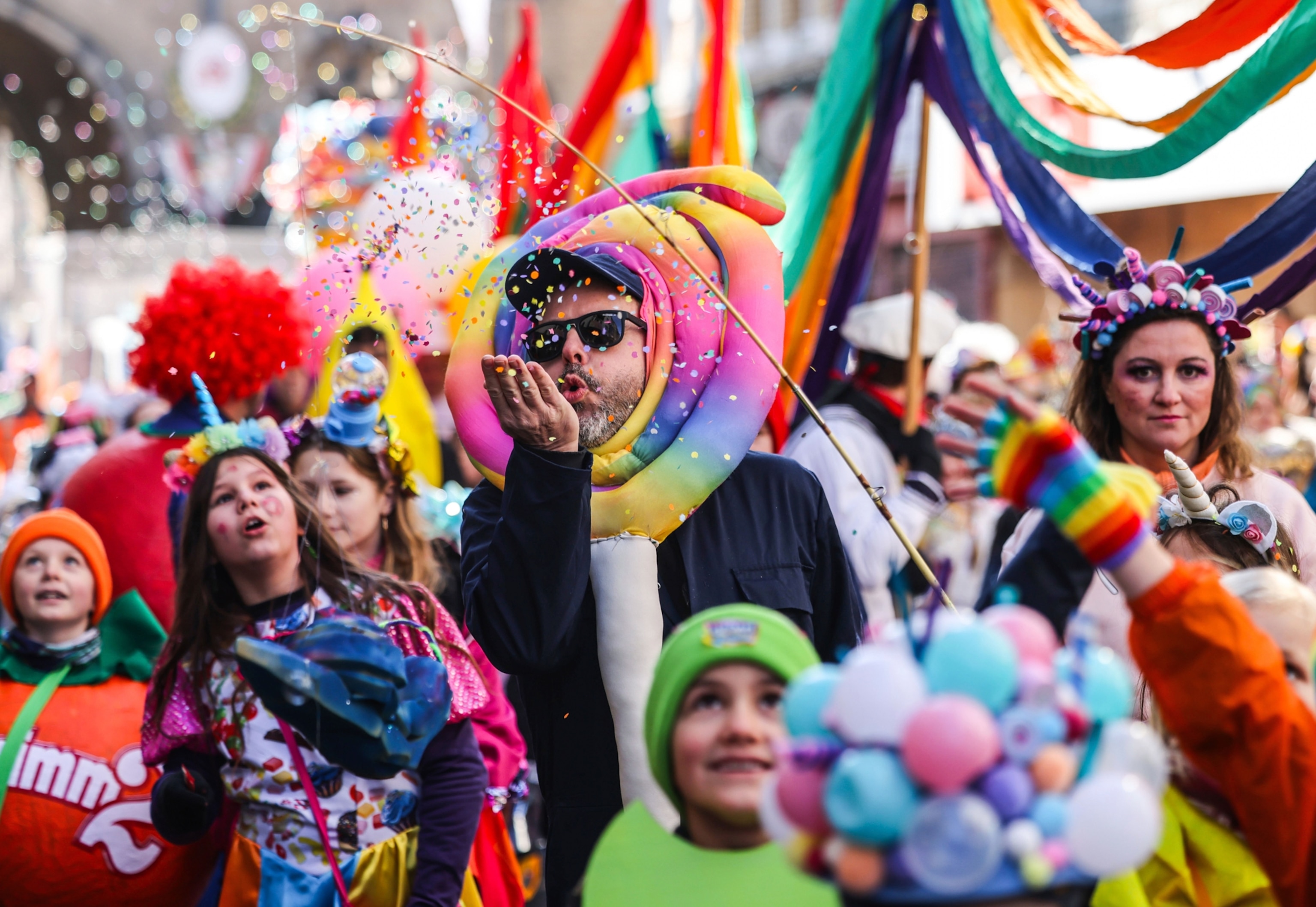 A man blows confetti in the crowd.