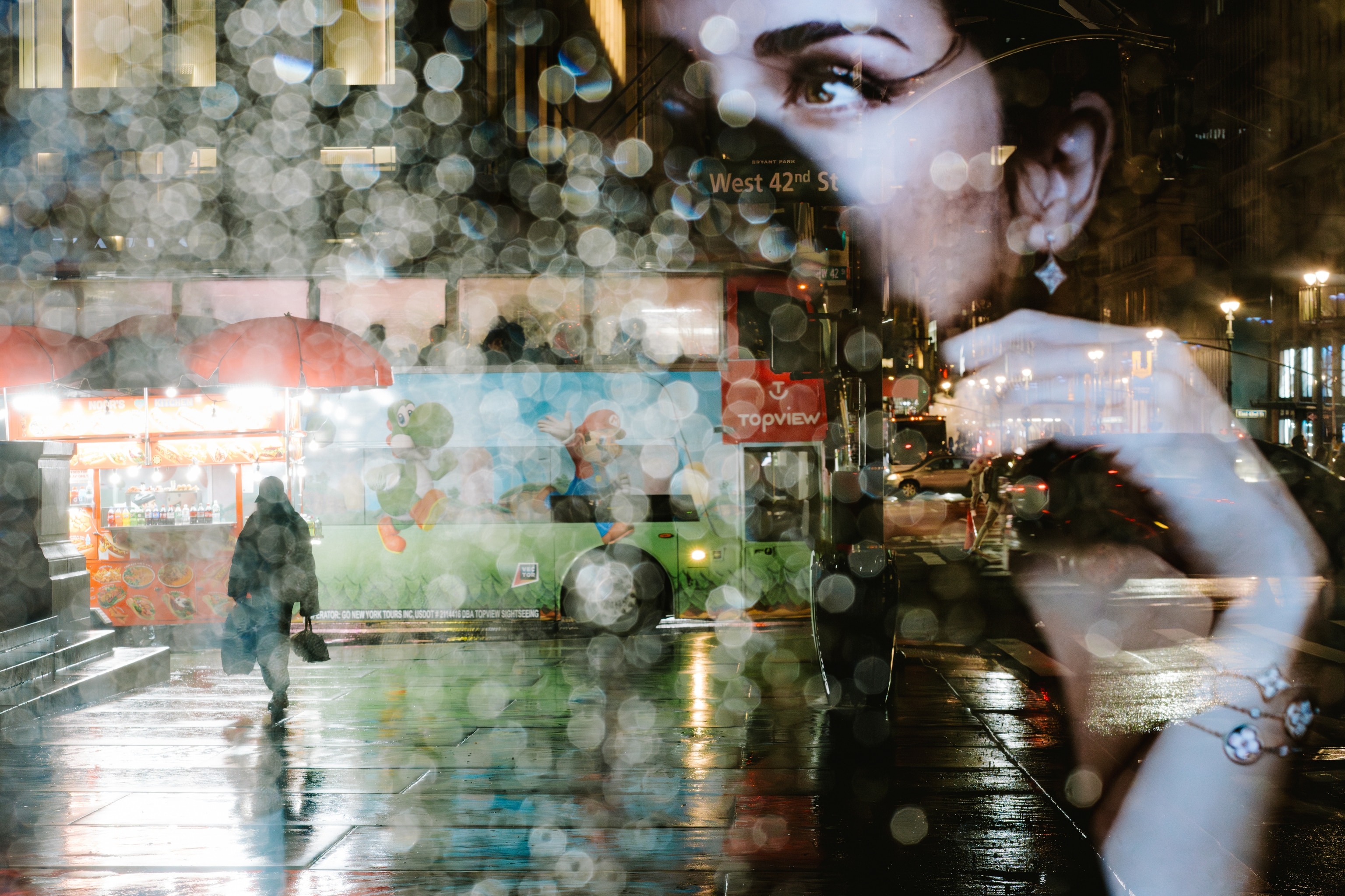 A person walking alone on a sidewalk in New York City on a rainy night.