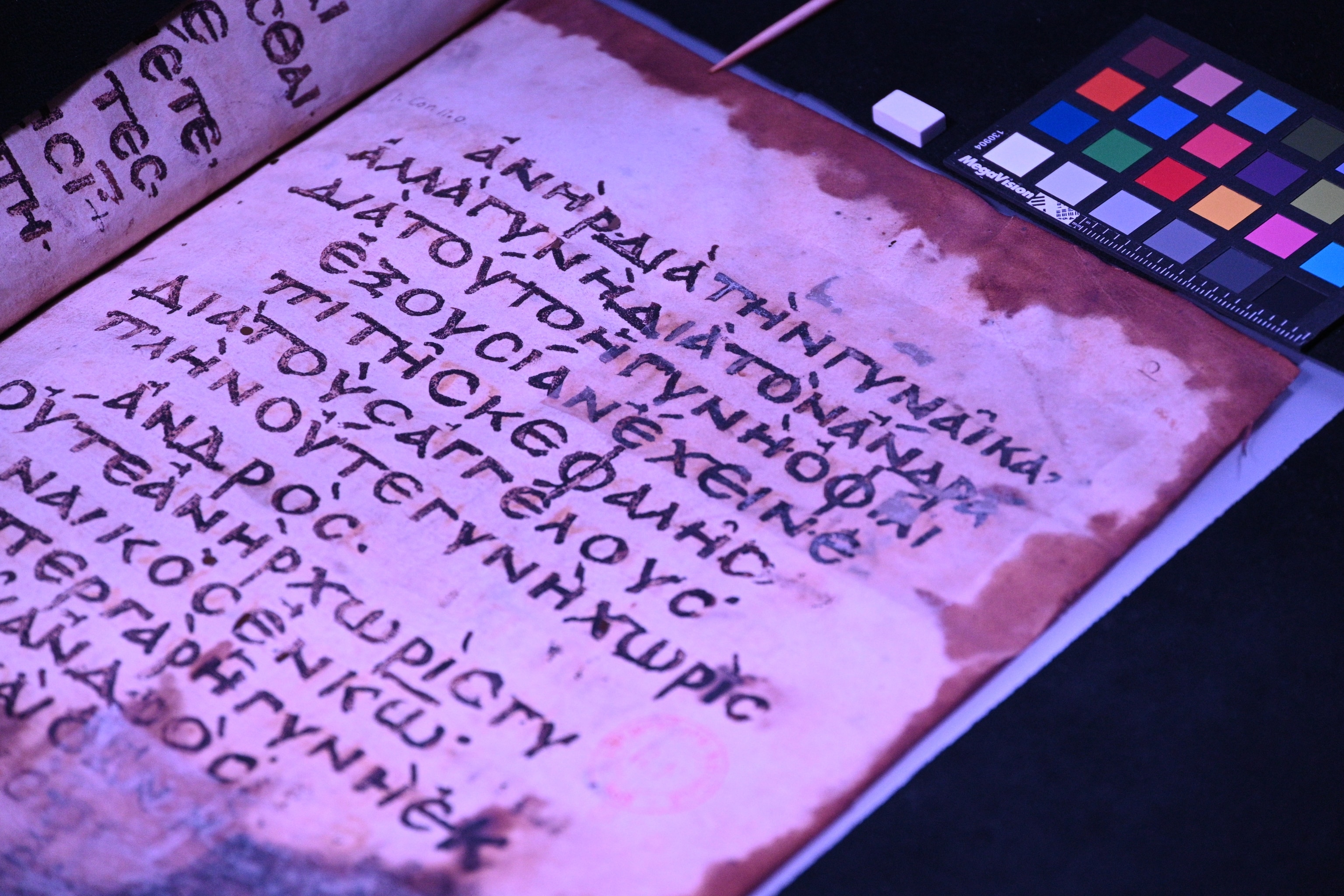 An up close photograph of an old manuscript, under purple lights 
