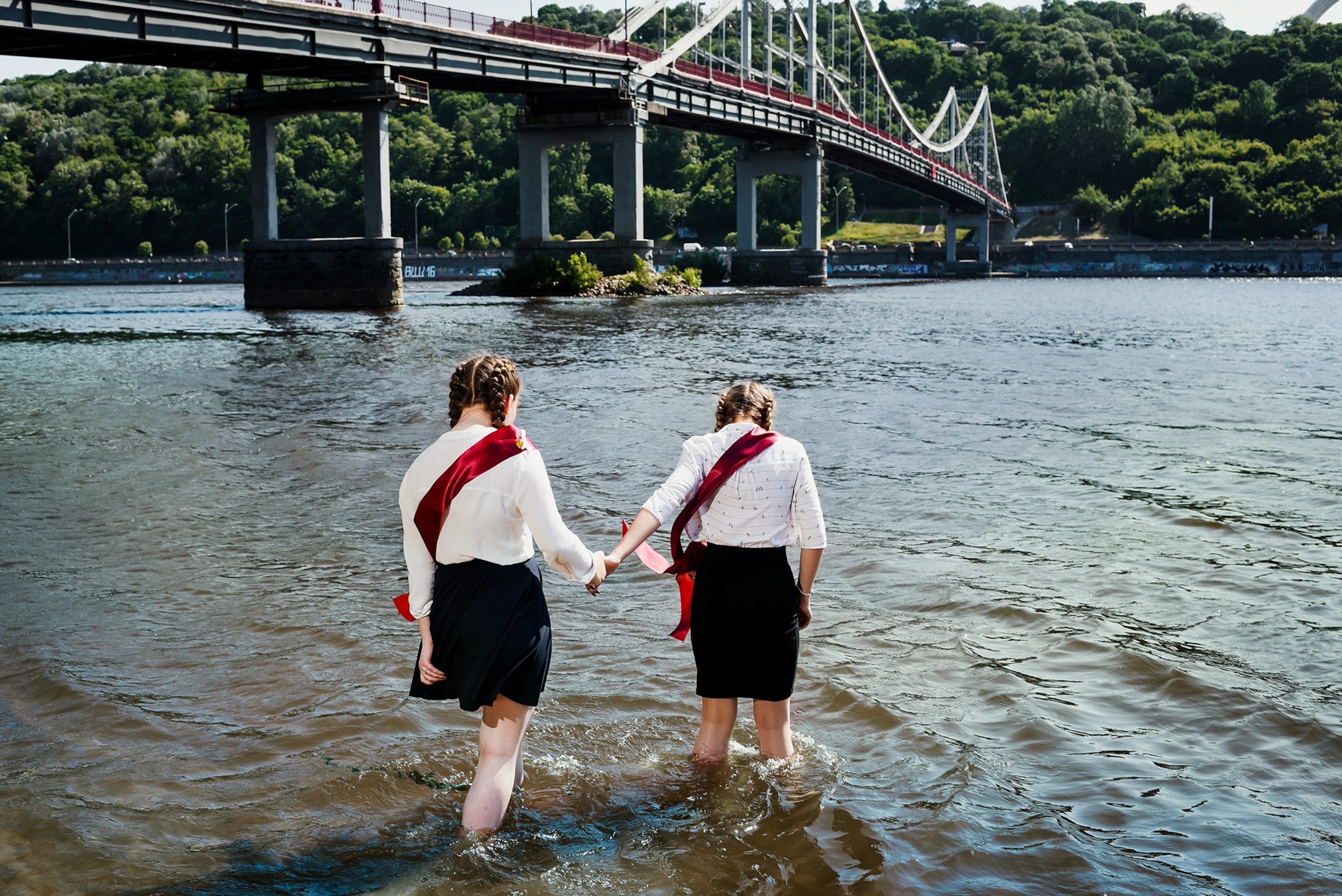 students wading in the Dnepr River after the last day of school in Kiev, Ukraine