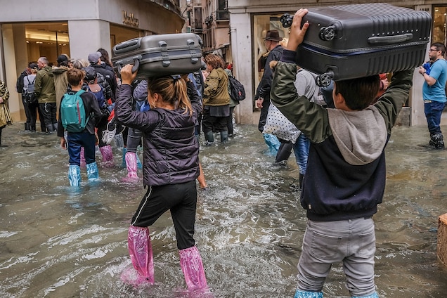 People carry their luggage over their heads to keep it as dry as possible.