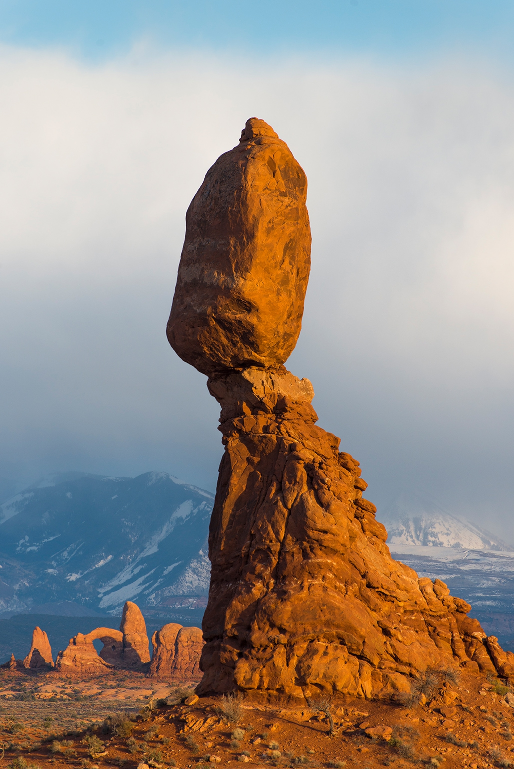 A tall rock with clouds and sky behind it