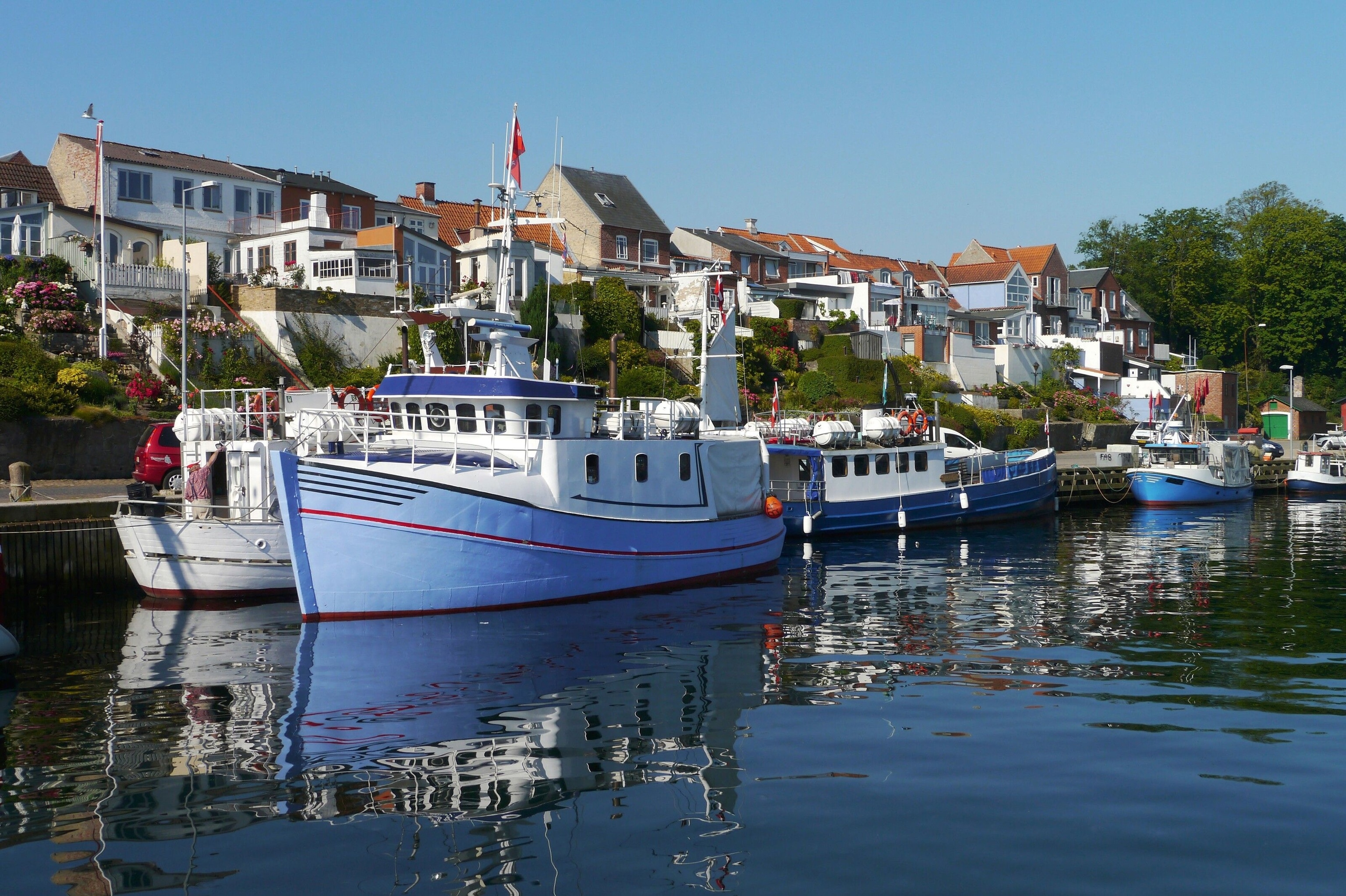 The port of Middelfart, Denmark, the 2022 European Destination of Excellence. It is full of blue and white fishing boats.