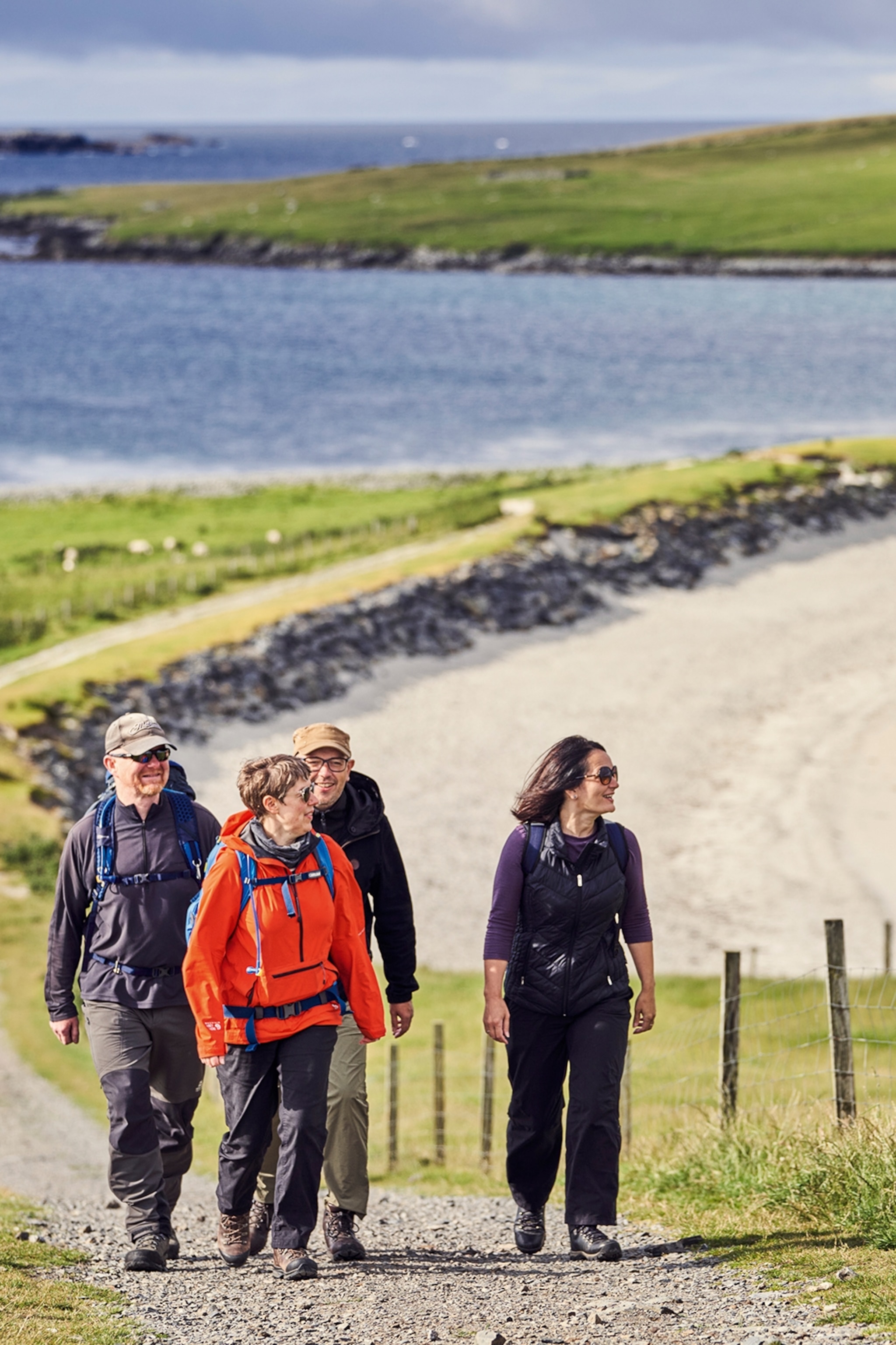 A group of hikers going up a trail with a coast line in the background.