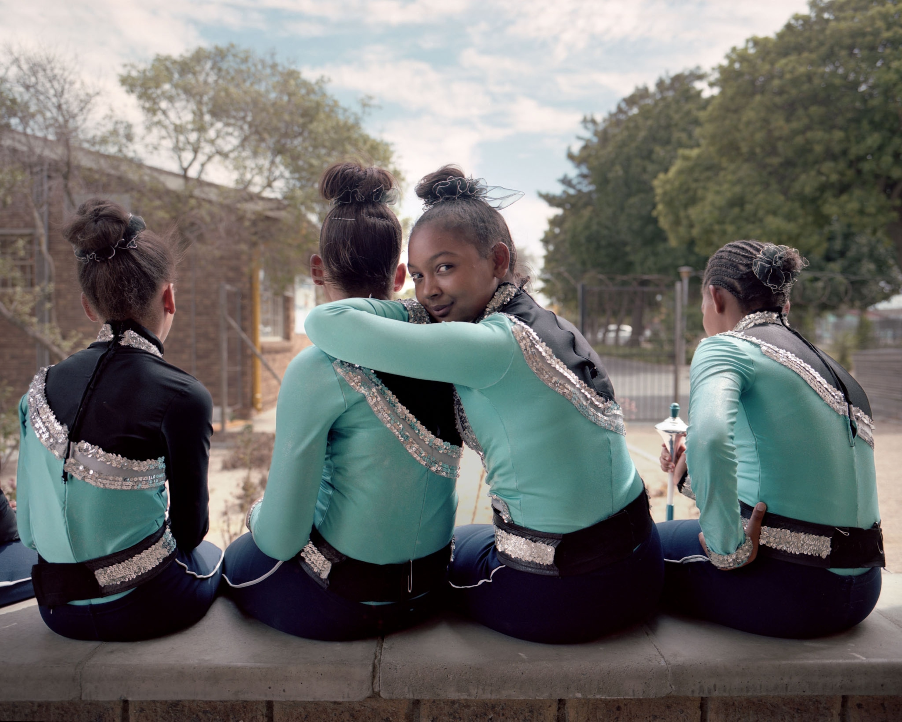 four girls sitting on a ledge with one looking back at the camera