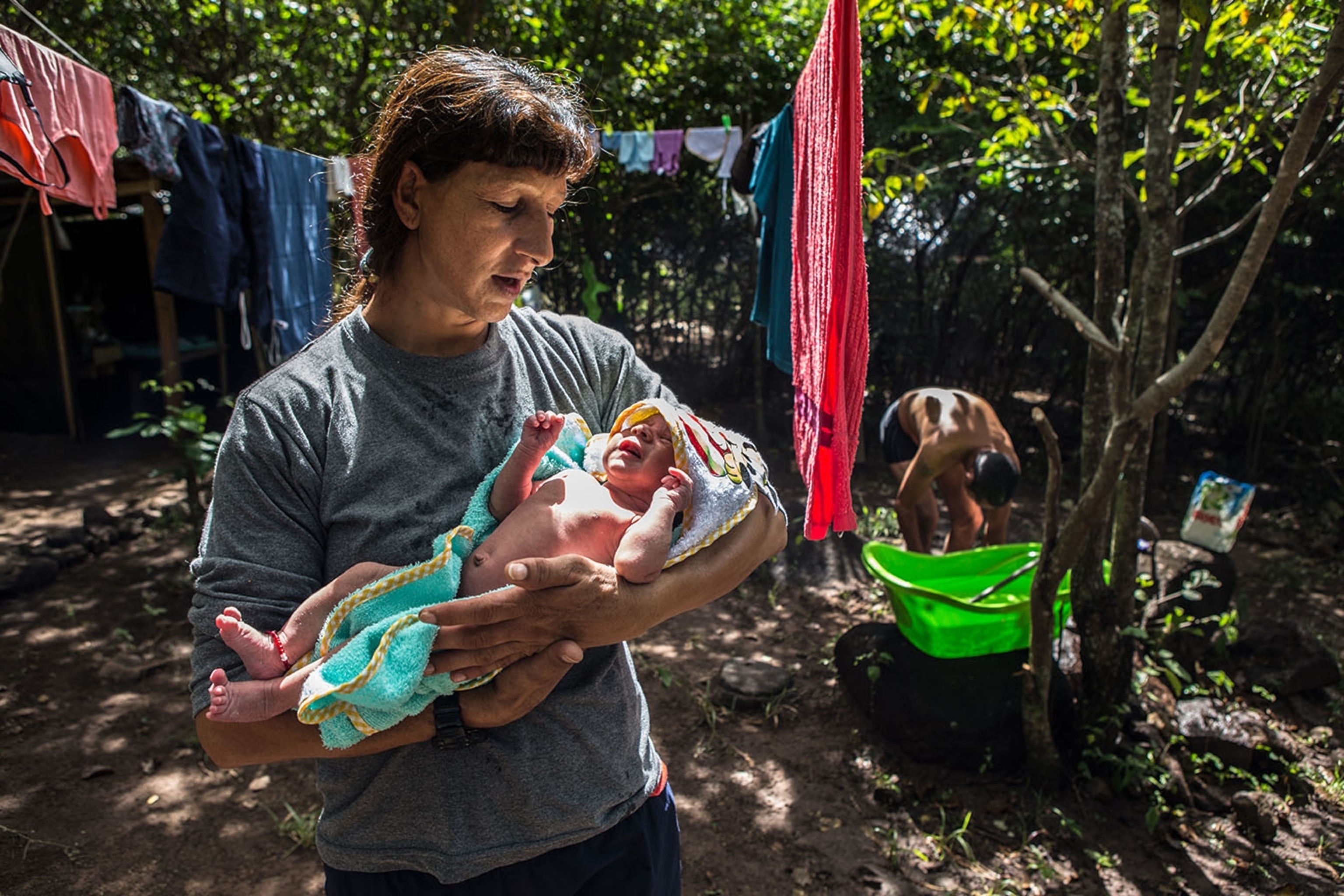 a woman holding a new born baby out in the jungle