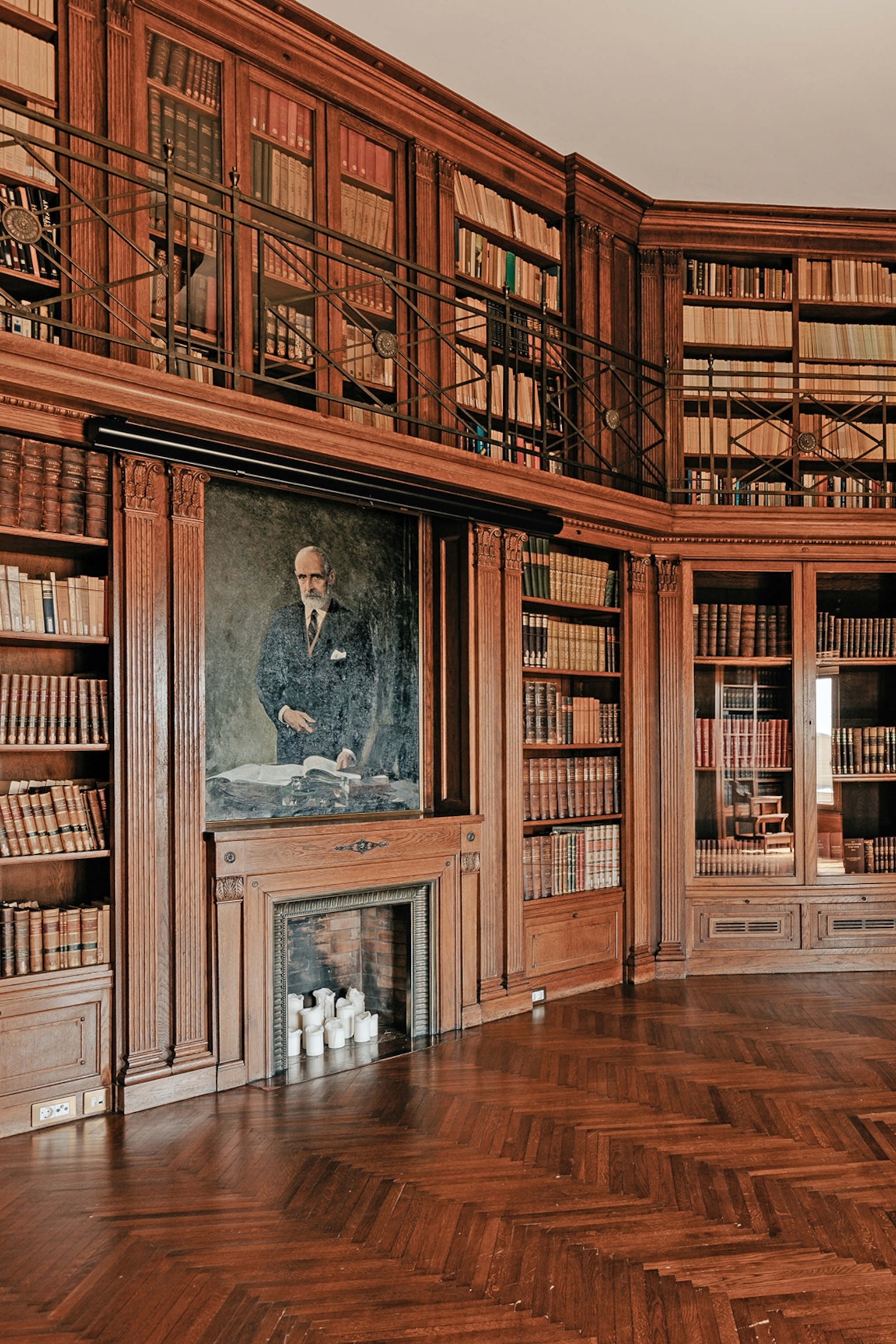 A wooden and multi-level library with a fire place and portrait of politician Francesc Cambó.