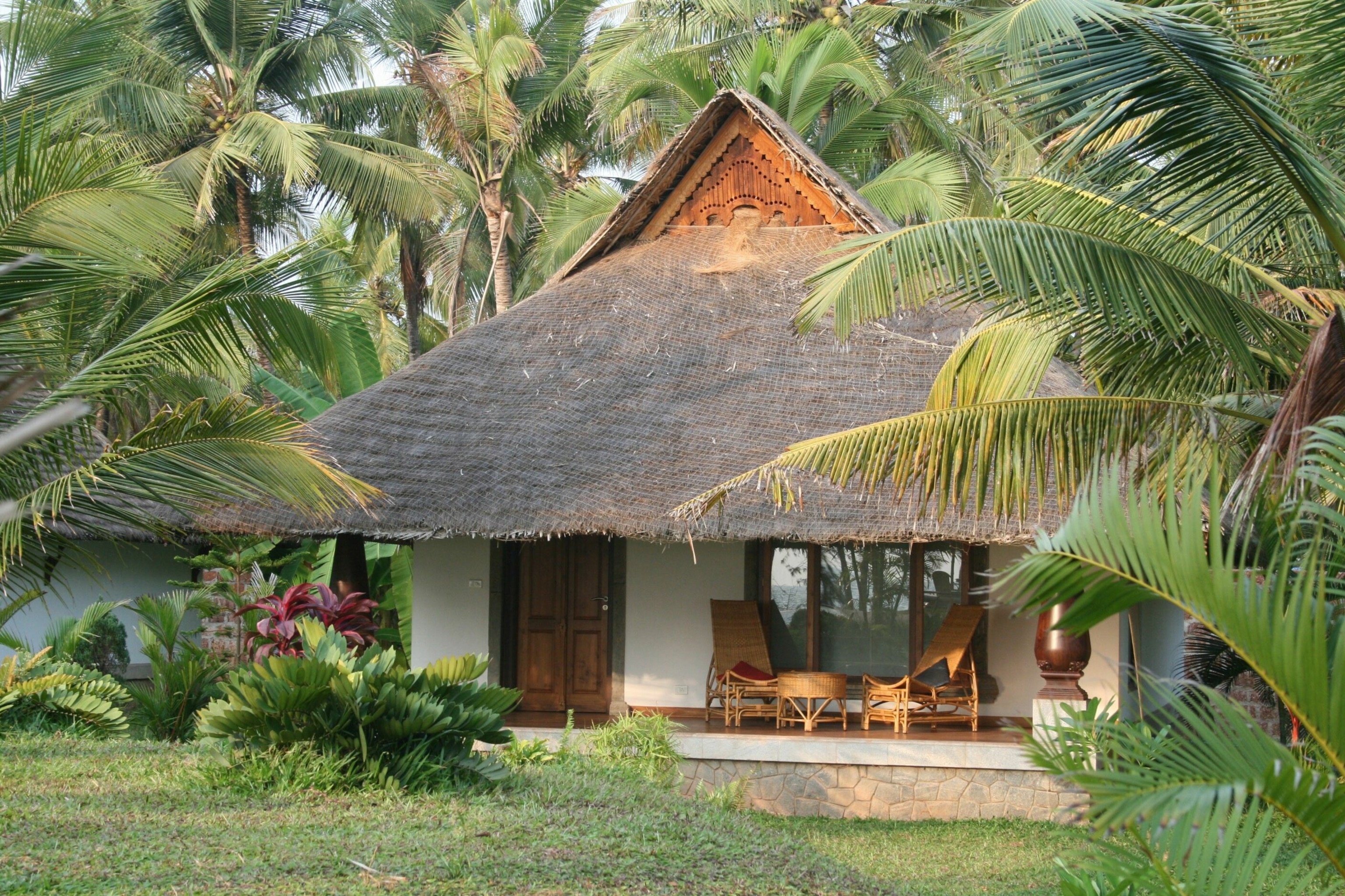 A Neeleshwar Hermitage cottage surrounded by palm trees