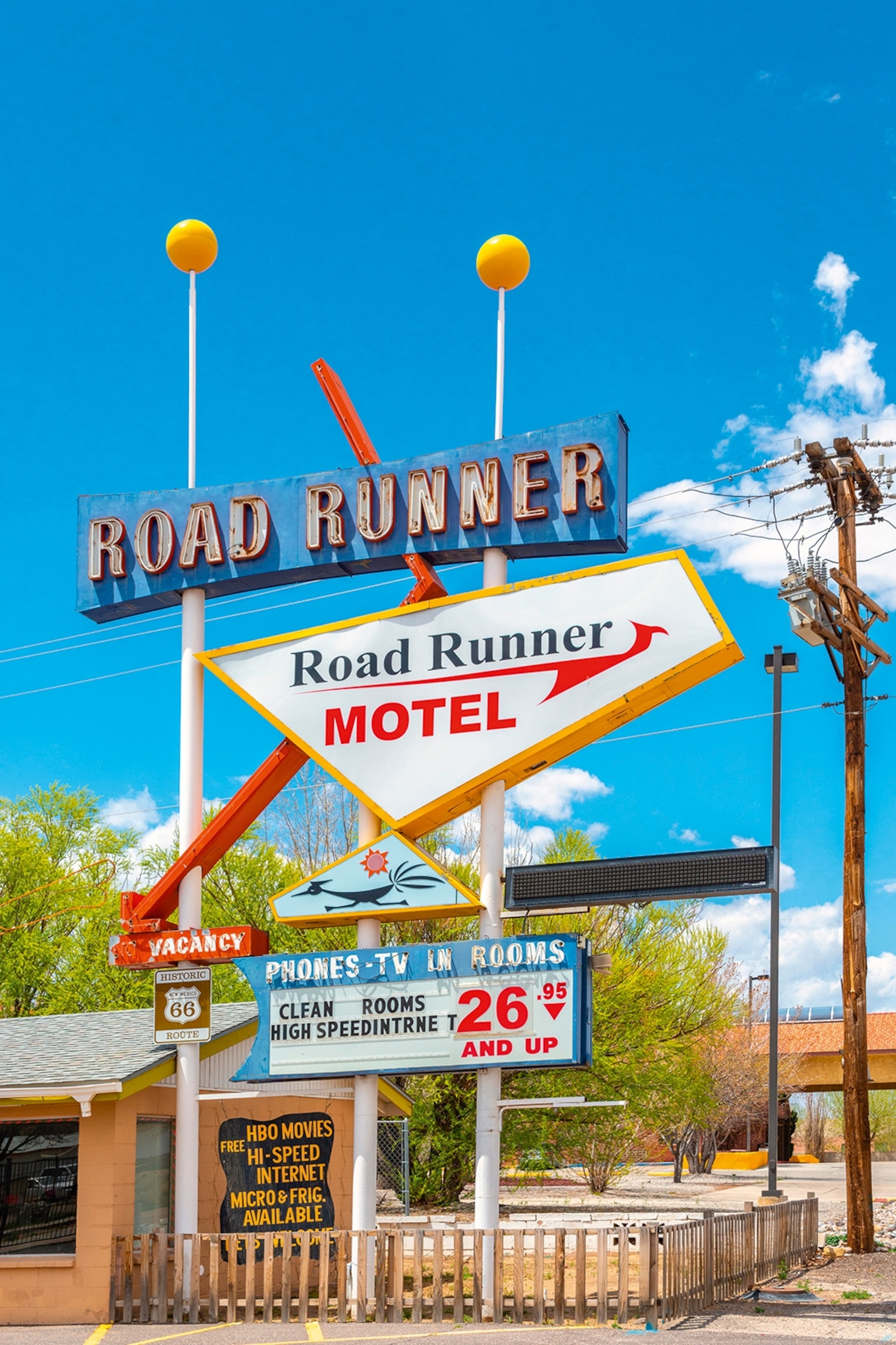 A multi-tiered sign for 'Roadrunner' Motel on Route 66 on a sunny day.