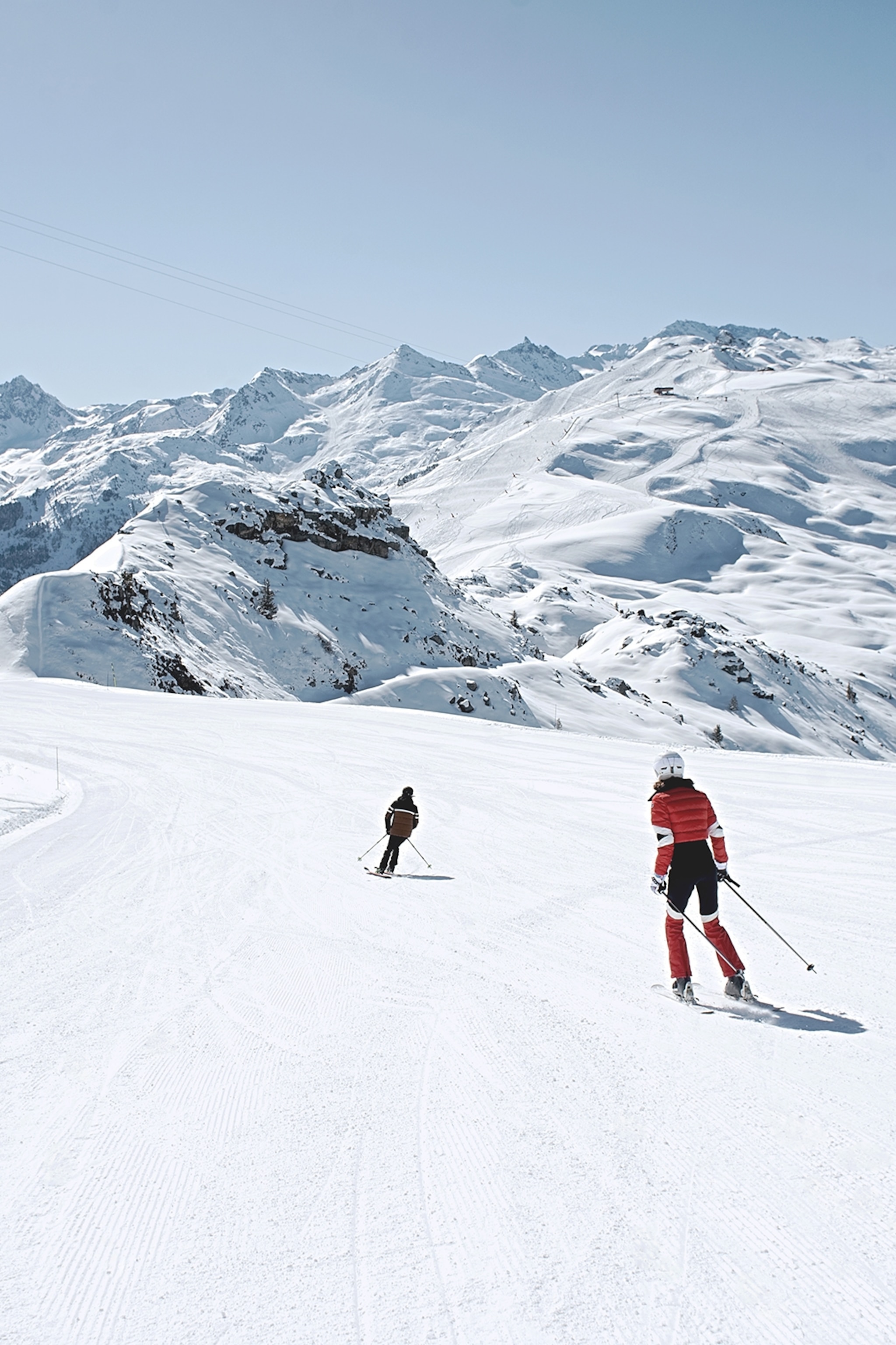 Two skiers descending a quiet and clean piste in the French Alps.