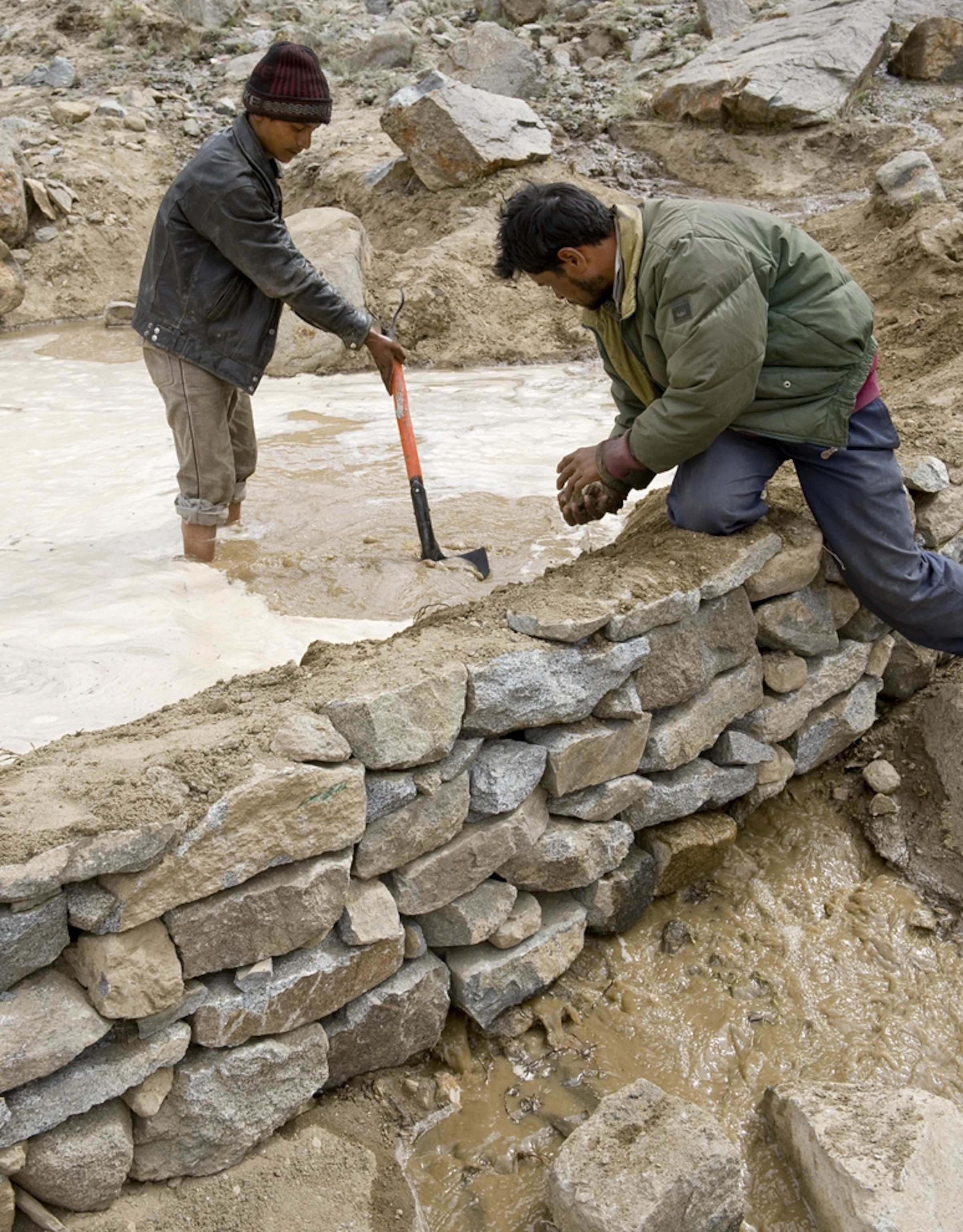 Two workers create an embankment in Stakmo, Ladakh, India, that will contain an artificial glacier.