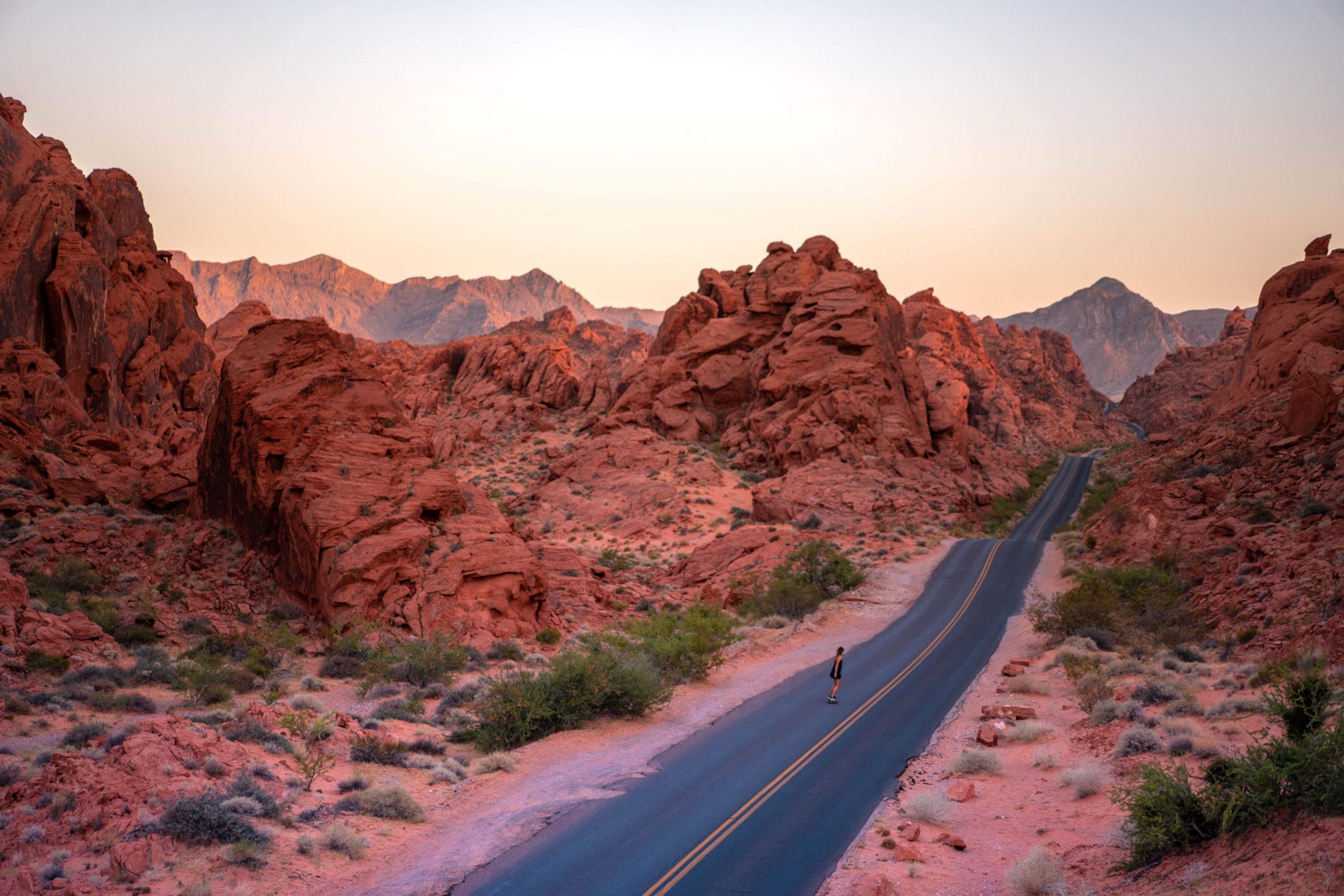 A woman skateboards down an empty desert road in Valley of Fire State Park.