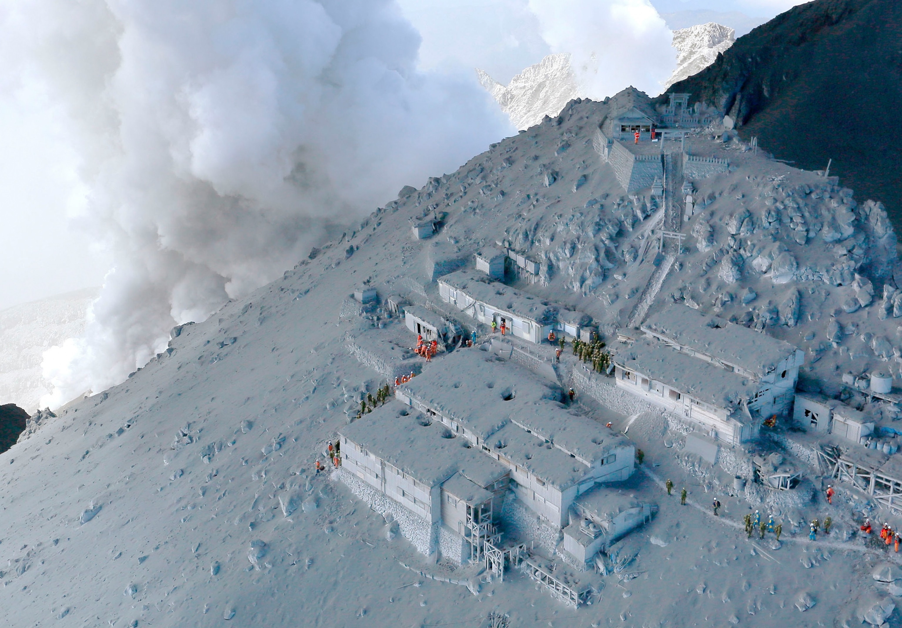 Japan Self-Defense Force (JSDF) soldiers and firefighters conducting rescue operations at mountain lodges, covered with volcanic ash.